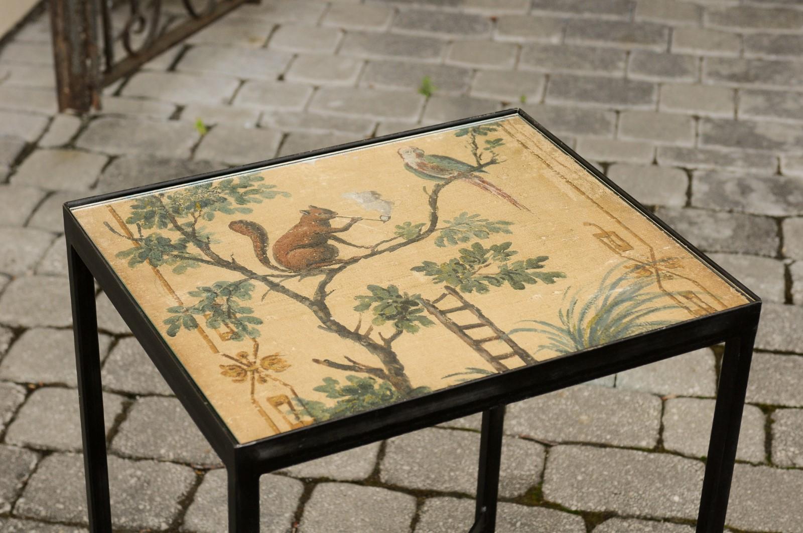 A contemporary chinoiserie style side table made from an antique 1870s screen depicting a squirrel and a bird, mounted on a custom iron stand. We currently have four tables available of two slightly different dimensions available. This stylish