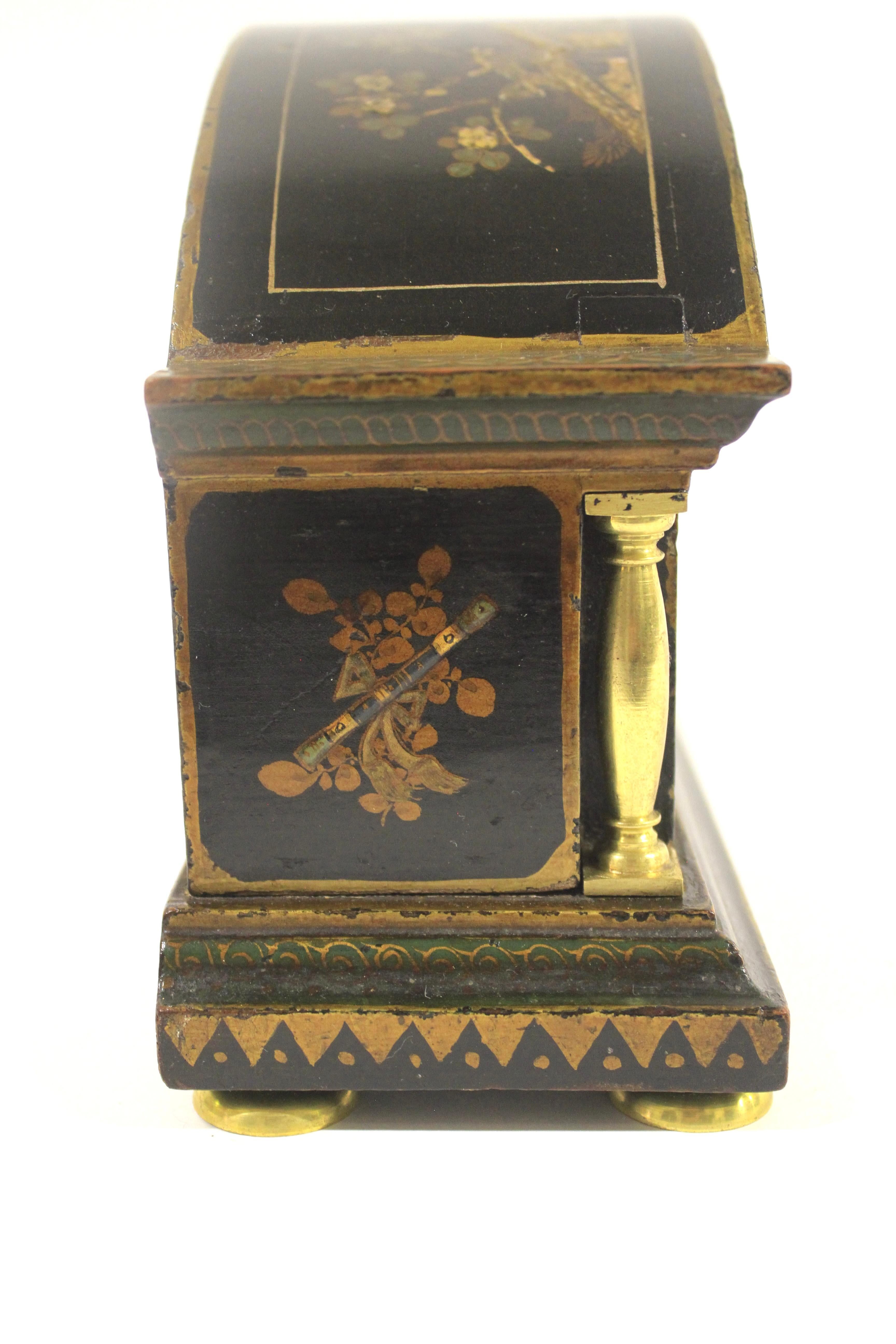 Horloge de cheminée décorée en Chinoiserie circa 1920
Fond noir avec décoration dorée
Dessus en forme de dôme, avec des colonnes en laiton doré de chaque côté. 
Face à dôme en émail crème ,
Verre dôme biseauté, bord en laiton doré,
Mouvement