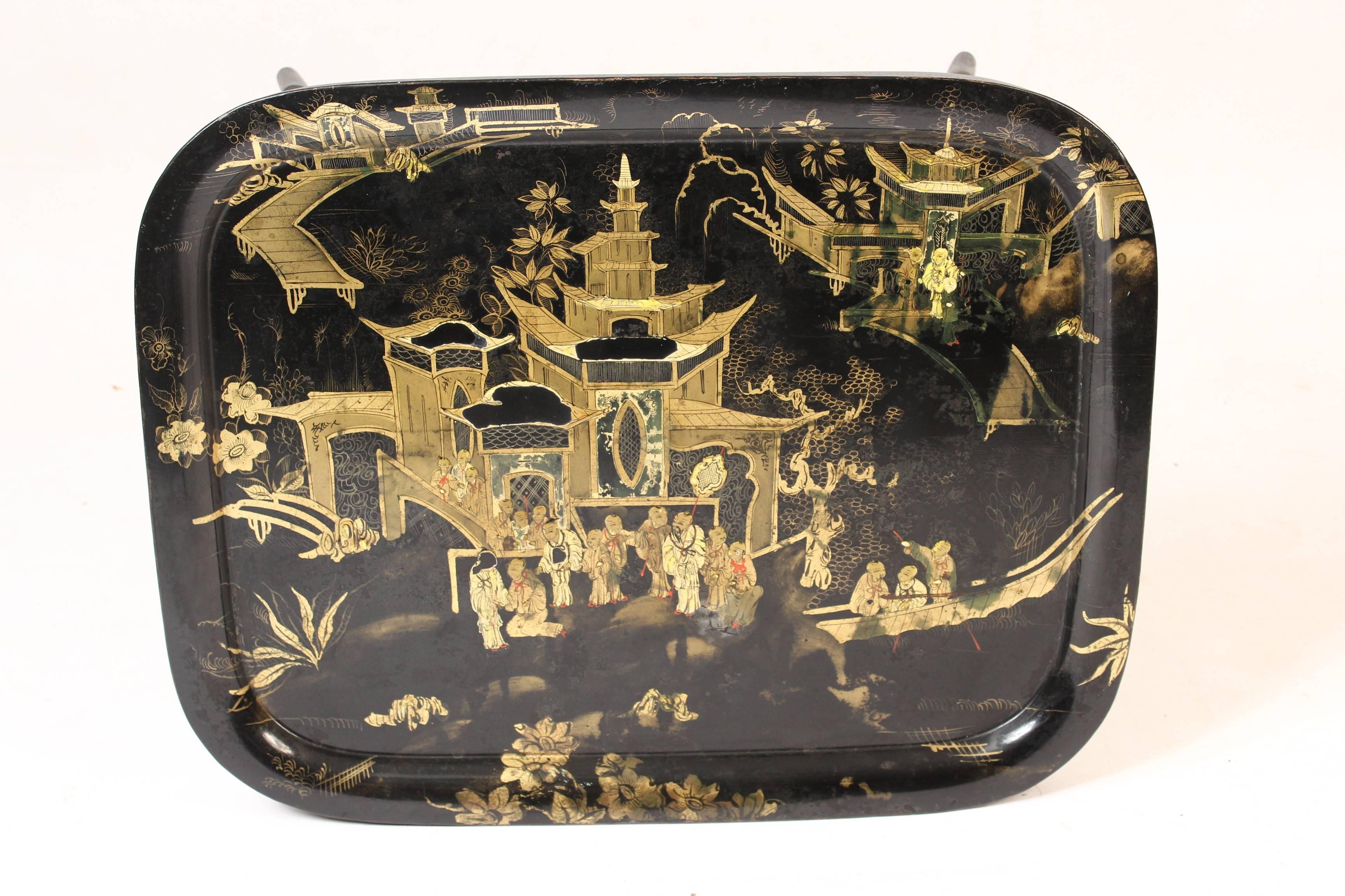 Chinoiserie decorated tole tray table with raised decorations, late 19th century. The English Regency style black painted bamboo style stand is fourth quarter of the 20th century.