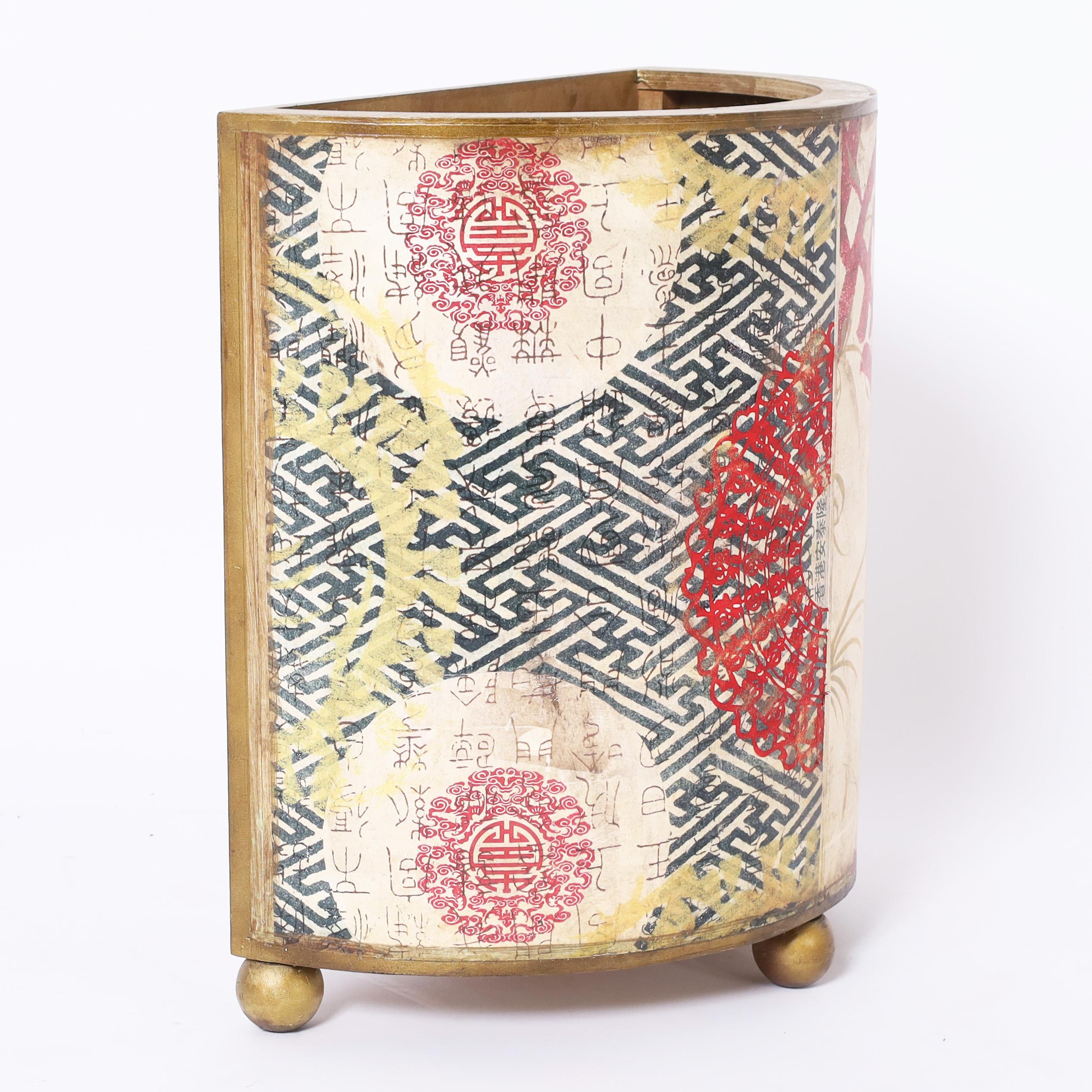 Chic mid century trash can crafted in wood decorated with lithographic chinese characters against geometric and floral designs set on ball feet.
