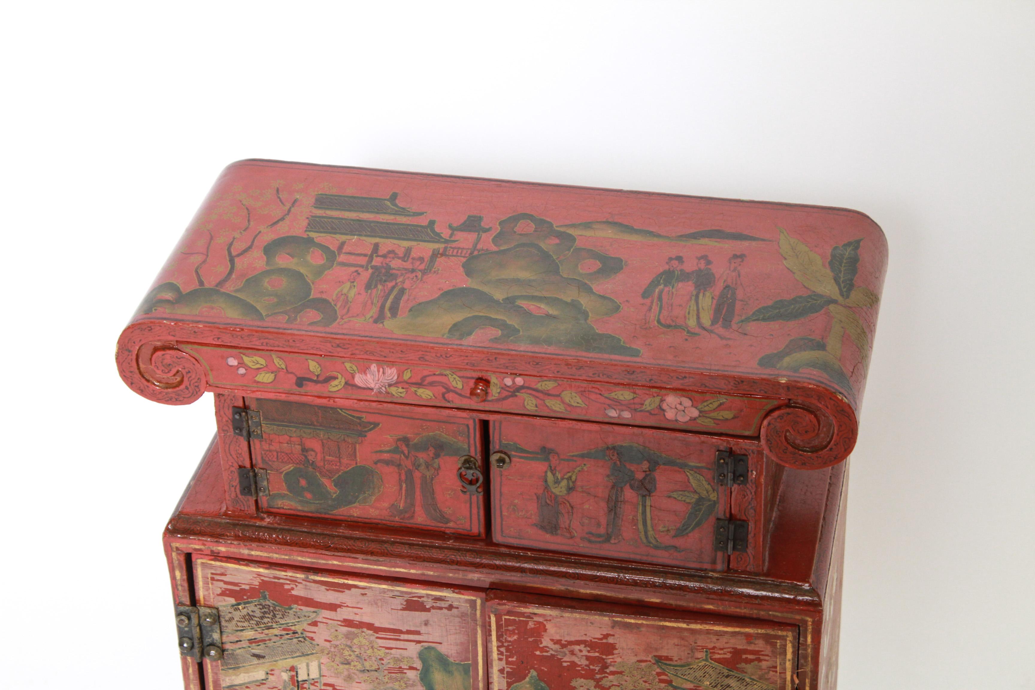 Chinoiserie red and figural painted diminutive cabinet with two small doors over two larger doors, interior drawer and one at top.
Measures: 25.5