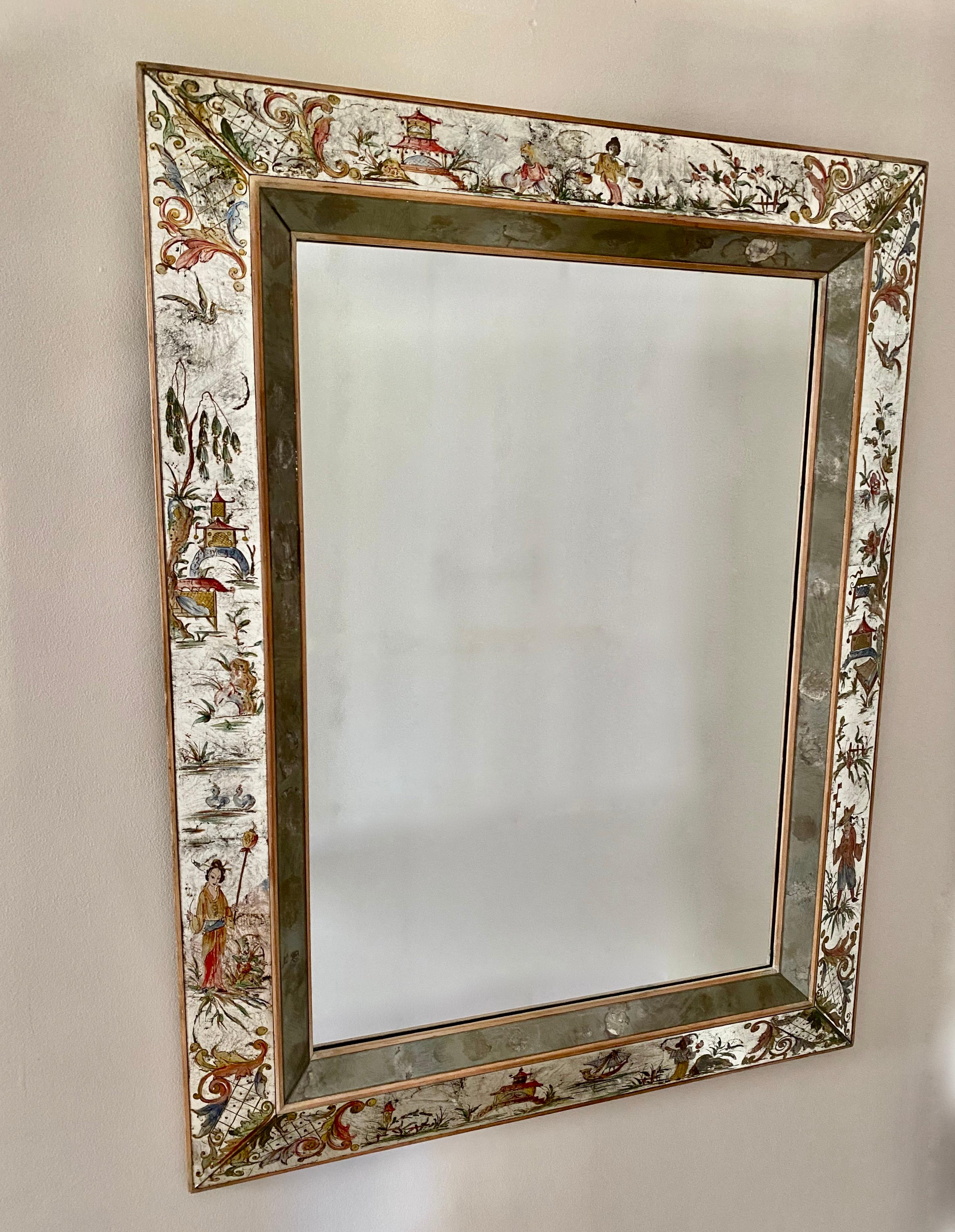 Large eglomisé wall mirror with charming and colorful hand reverse-painted Chinoiserie scenes and palladium silvered backing. Interior mirrored glass has fumed silvering. Exterior wood frame is in a neutral pickled finish. Painted decoration is