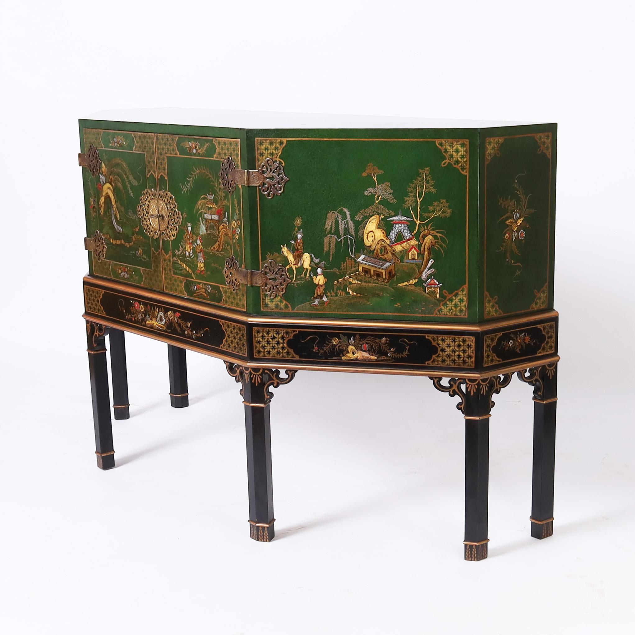 Impressive mid century two door cabinet on stand, lacquered in an alluring green and hand decorated in chinoiserie with elaborate brass hardware on a hand decorated black stand with six ming style legs. 