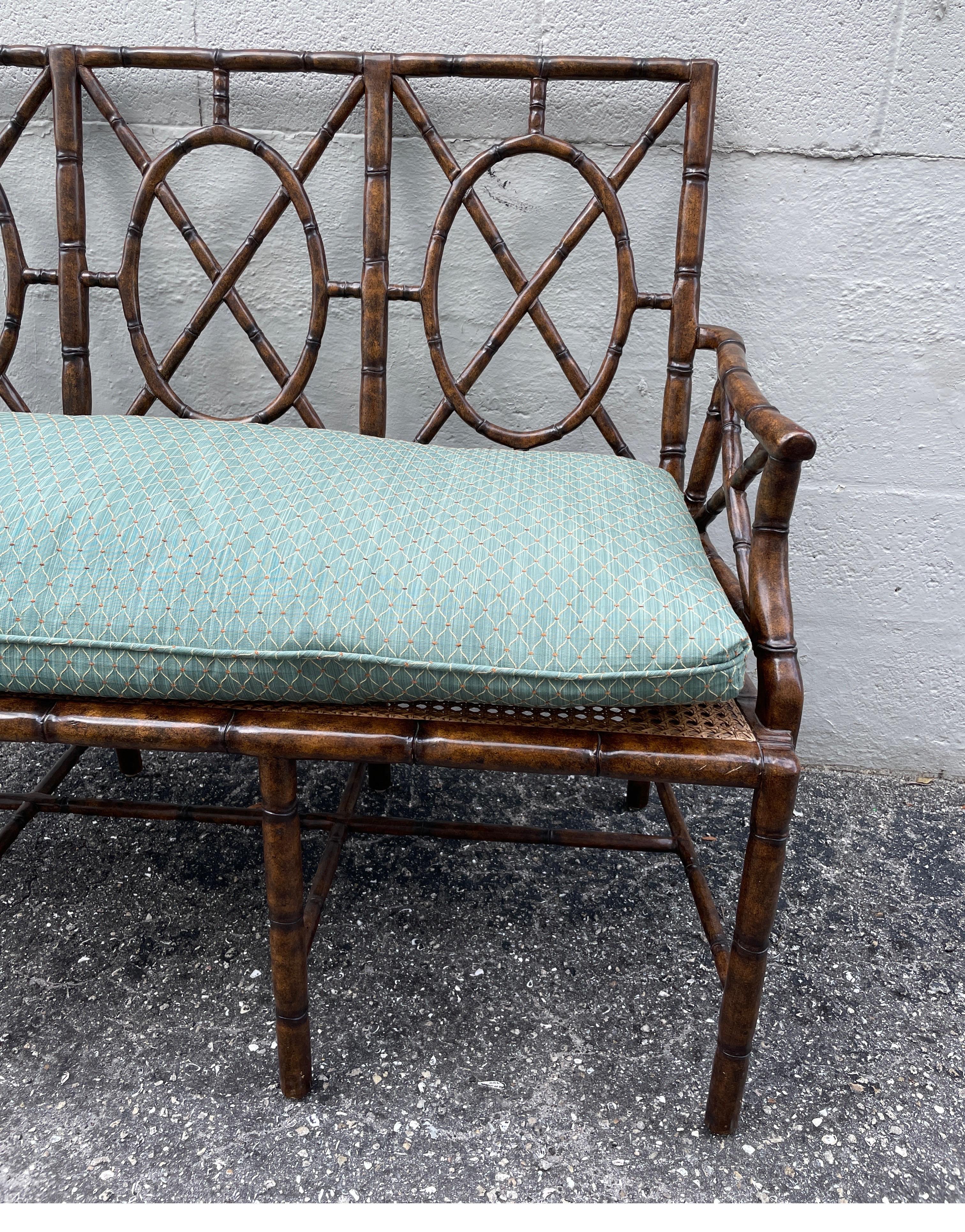 Chinoiserie inspired faux bamboo settee with caned seat & one cushion.