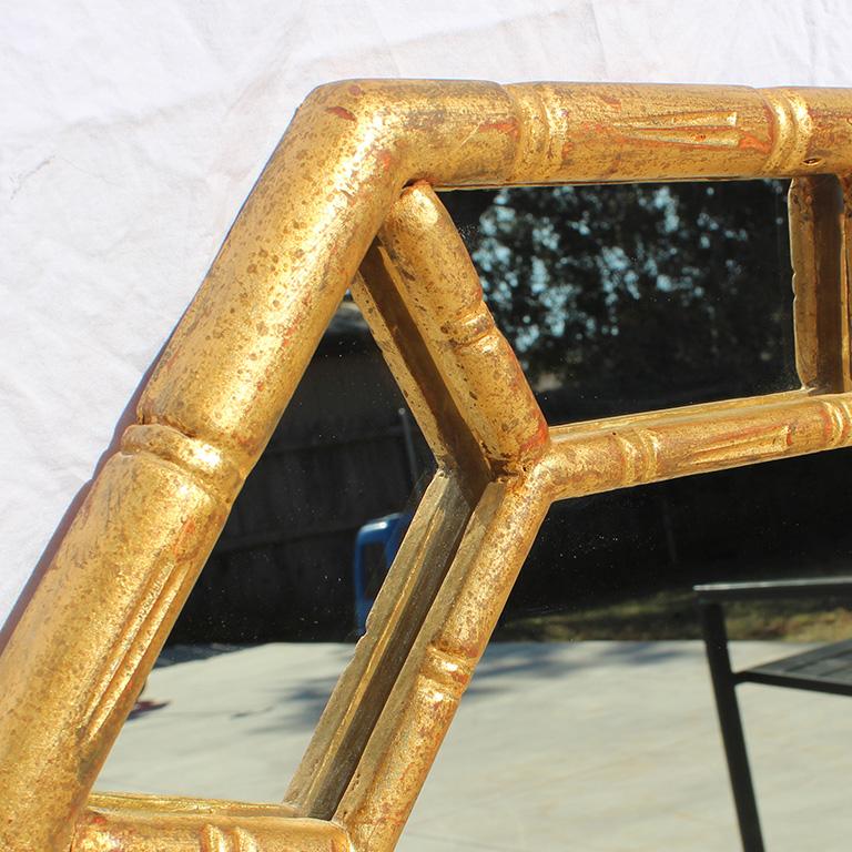 Chinoiserie faux bamboo gilded mirror, circa 1970. This octagonal-shaped mirror is in an octagonal shape with a giltwood gold frame. Frame mimics the popular designers' cult favorite of faux bamboo. The small inner frame is affixed on top of the