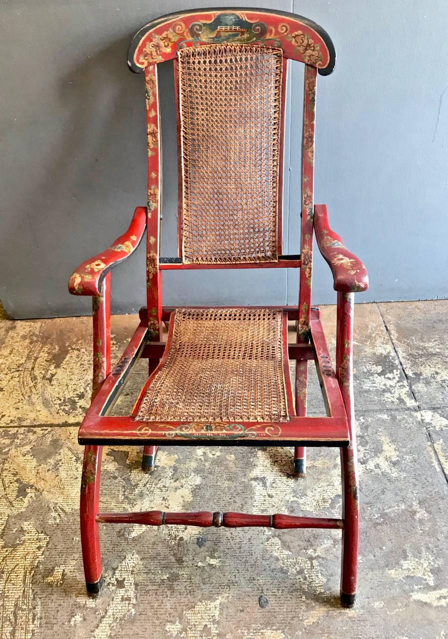 This is a highly decorative red chinoiserie painted and caned folding chairs that dates to the late 19th or early 20th century. The chair is in overall very good condition and exhibits tons of character. The original caning is in good condition and