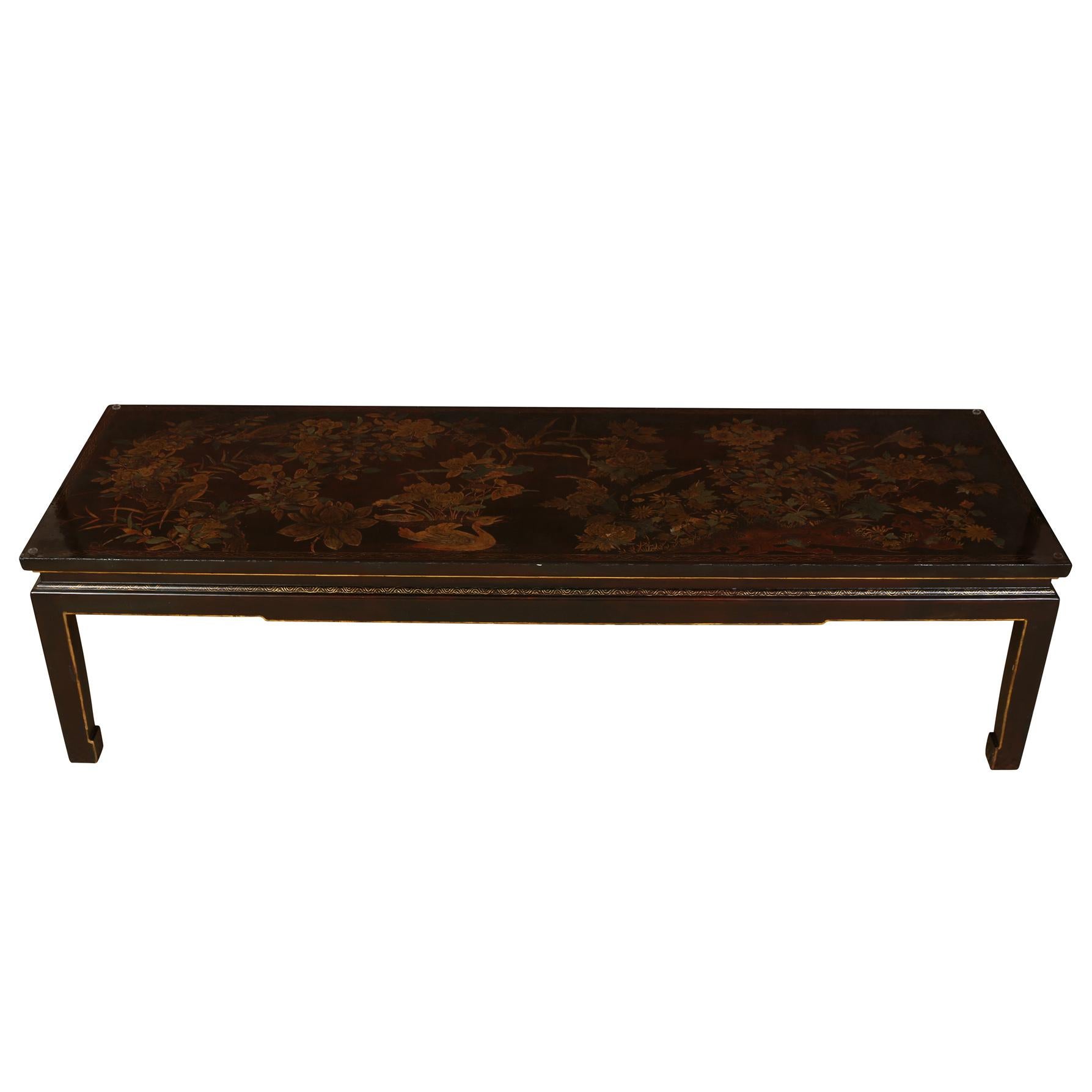 A vintage chinoiserie gilt decorated chocolate brown lacquered coffee table with a glass top.  Gilt decorations feature a floral motif with bouquets of flowers and birds.  Glass top makes this beautiful table functional in any room