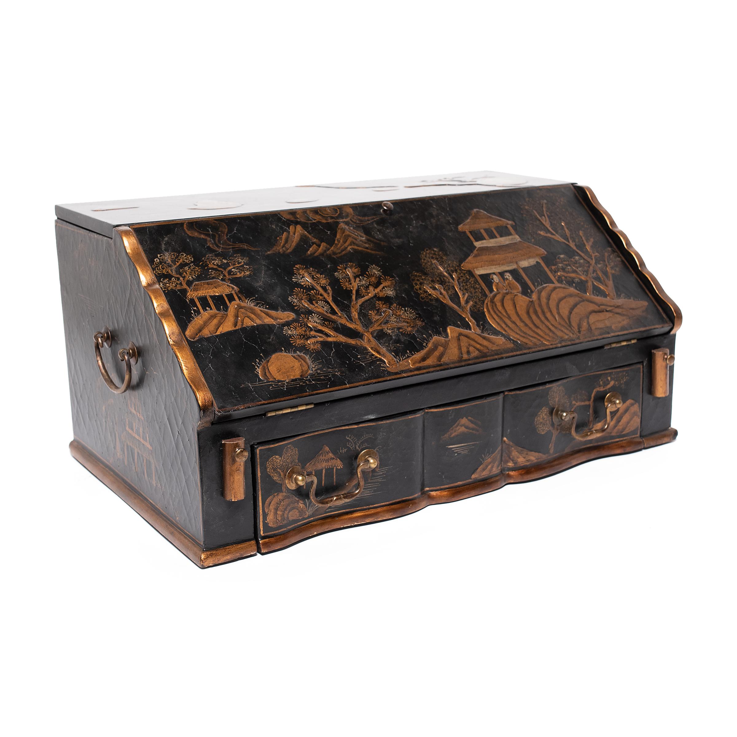 This charming tabletop secretaire is decorated in gold and black in the Chinoiserie style. The exterior is finished with black lacquer and painted with scenic mountain landscapes, brushed with gilt pigments atop low relief elements. At the base is a