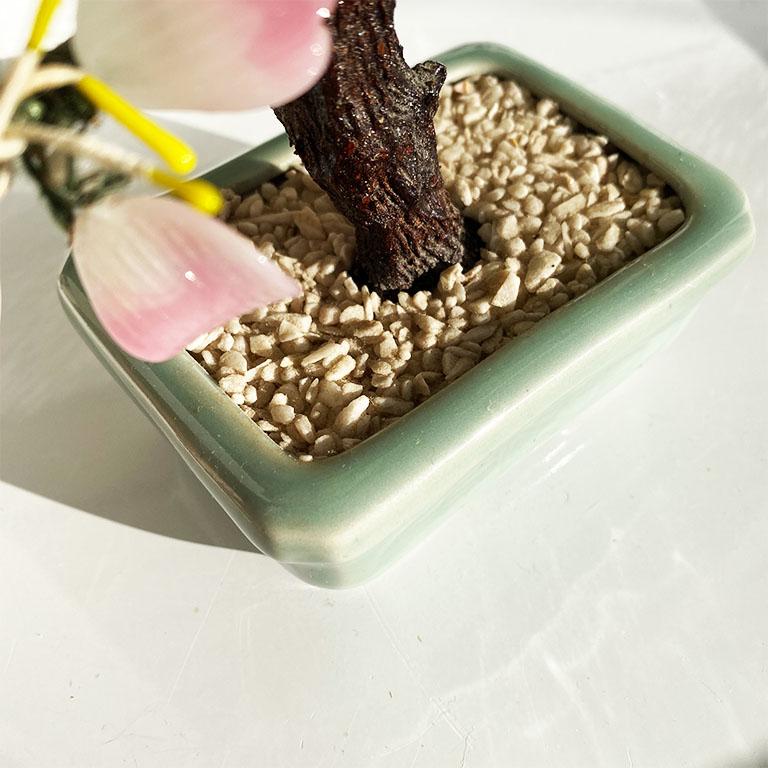 The vintage touch every room yearns for. With its semiprecious pink gemstone flowers, green jade color leaves and celadon pot, this lovely faux bonsai tree is the epitome of chinoiserie. Its faux bois tree trunk is firmly planted in a mint green