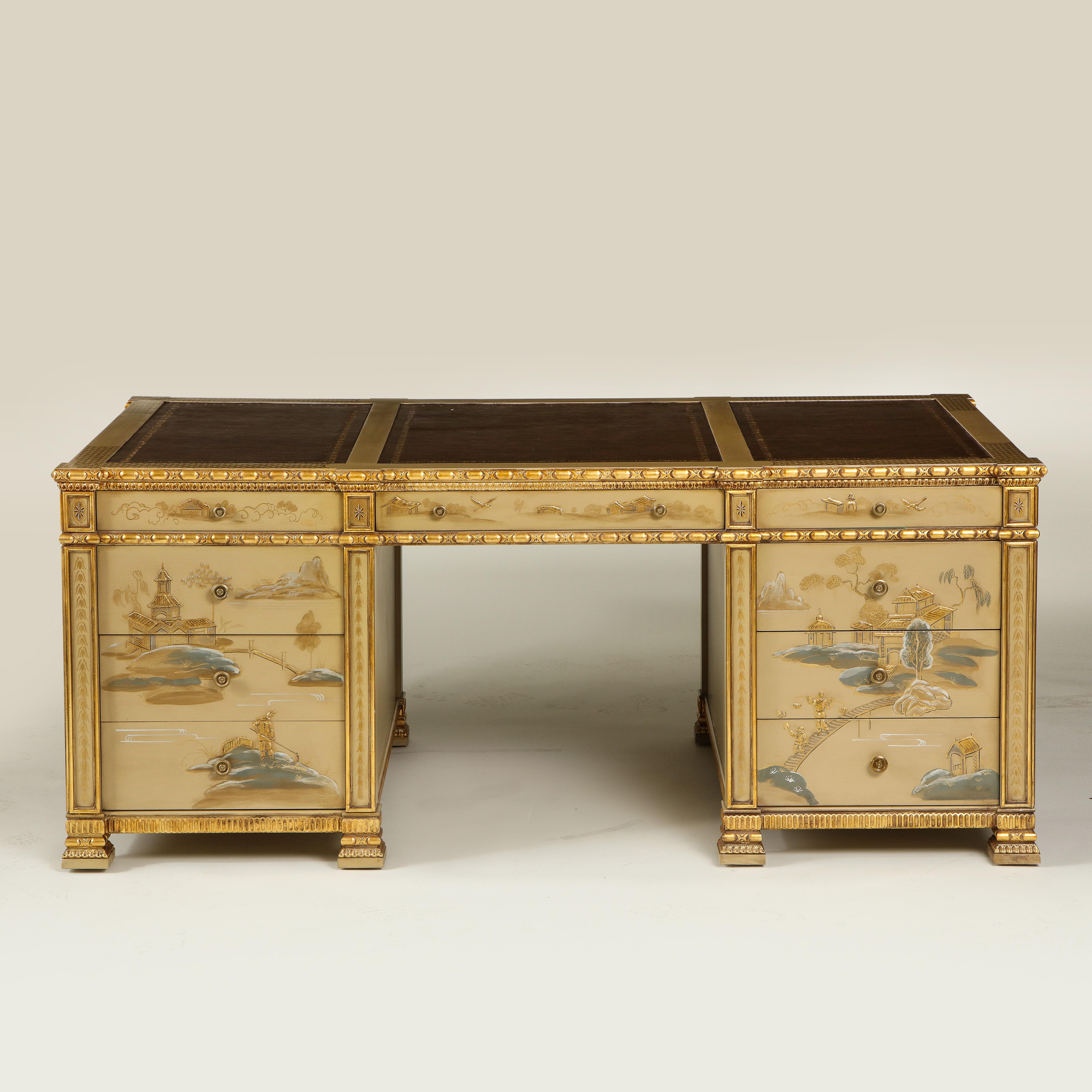 Handpainted on a warm beige-camel ground with gilt, blue, and white chinoiserie decoration including figures and birds in pagoda riverscapes; the rectangular top inset with gilt-tooled chocolate leather with gilt egg-and-dart carved edge; each side