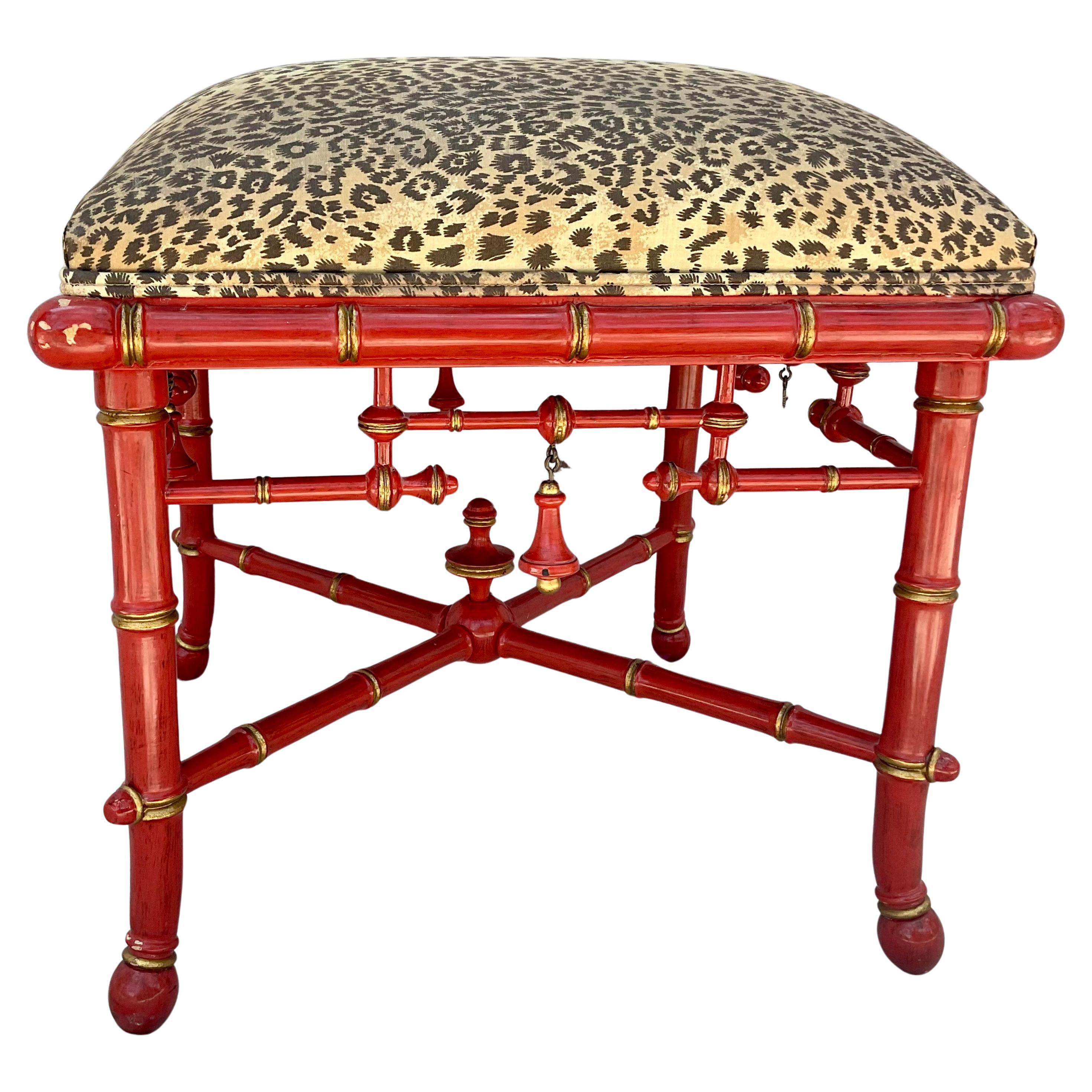 20th Century Chinoiserie Lacquered Faux Bamboo Square Foot Stool by Baker Furniture. Footstool features red lacquered faux bamboo wood with gilt accents.  Frame has turned finials and a cross-stretcher base. Seat is upholstered in luxurious leopard