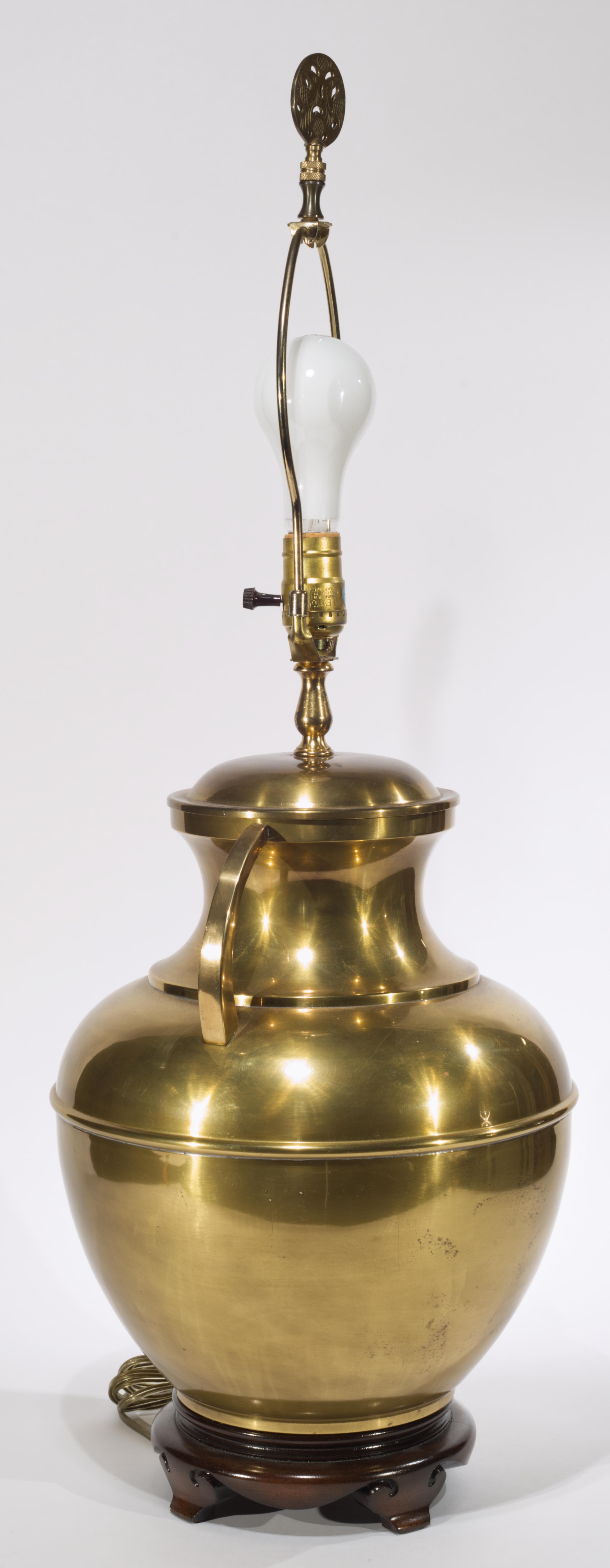  Vintage brass table lamp features an urn shaped base in Chinoiserie style; the rounded, arched handles and stepped elements on the shoulder of the urn show strong Streamline Moderne and Art Deco styles influence. The large, substantial lamp stands