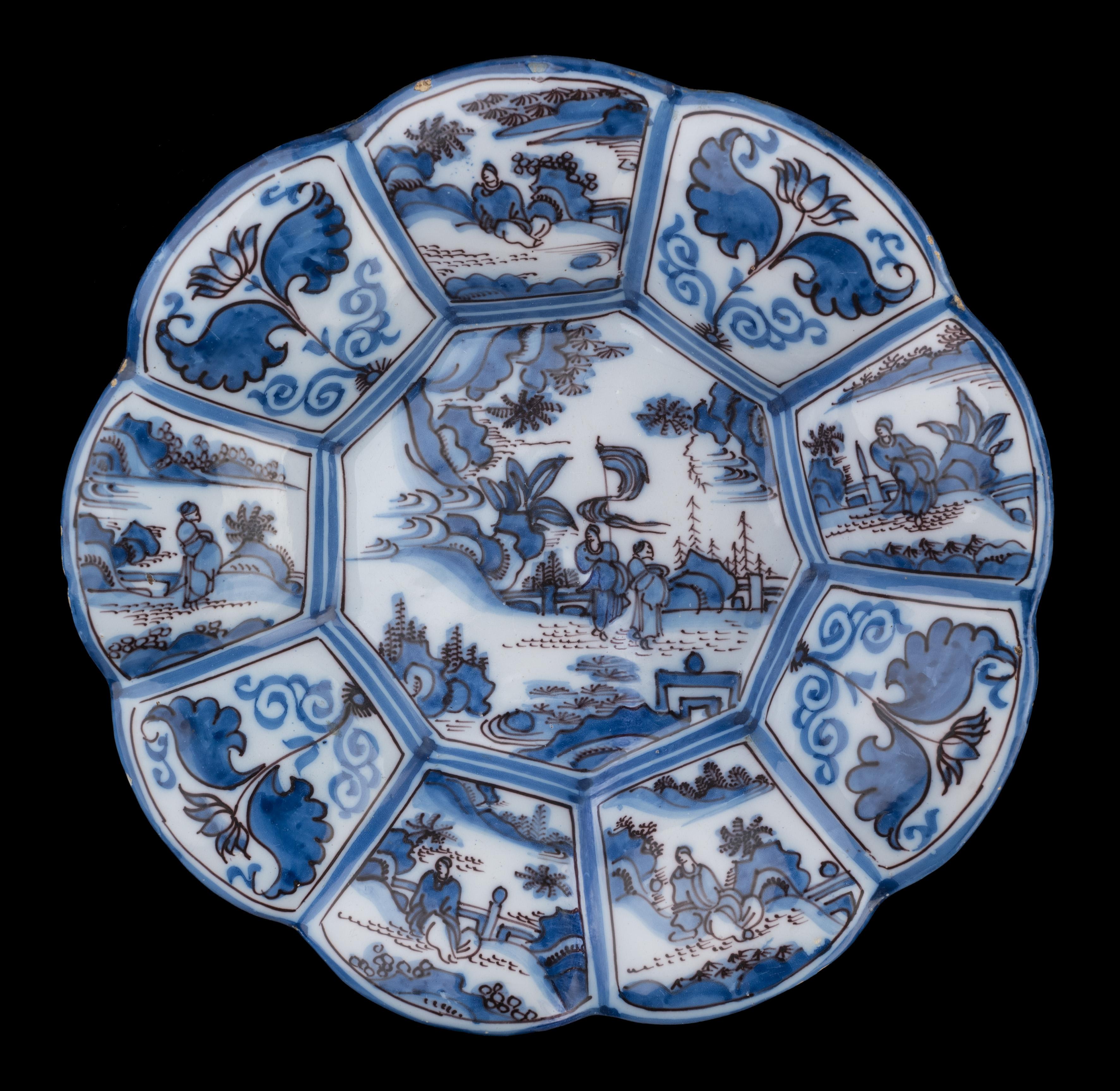 Chinoiserie lobed dish in blue and purple. Delft, circa 1680
Dimensions: diameter 34,5 cm / 13.58 in. 

The lobed dish is composed of nine, wide lobes and is painted in the centre with two Chinese figures with a banner in an oriental rocky