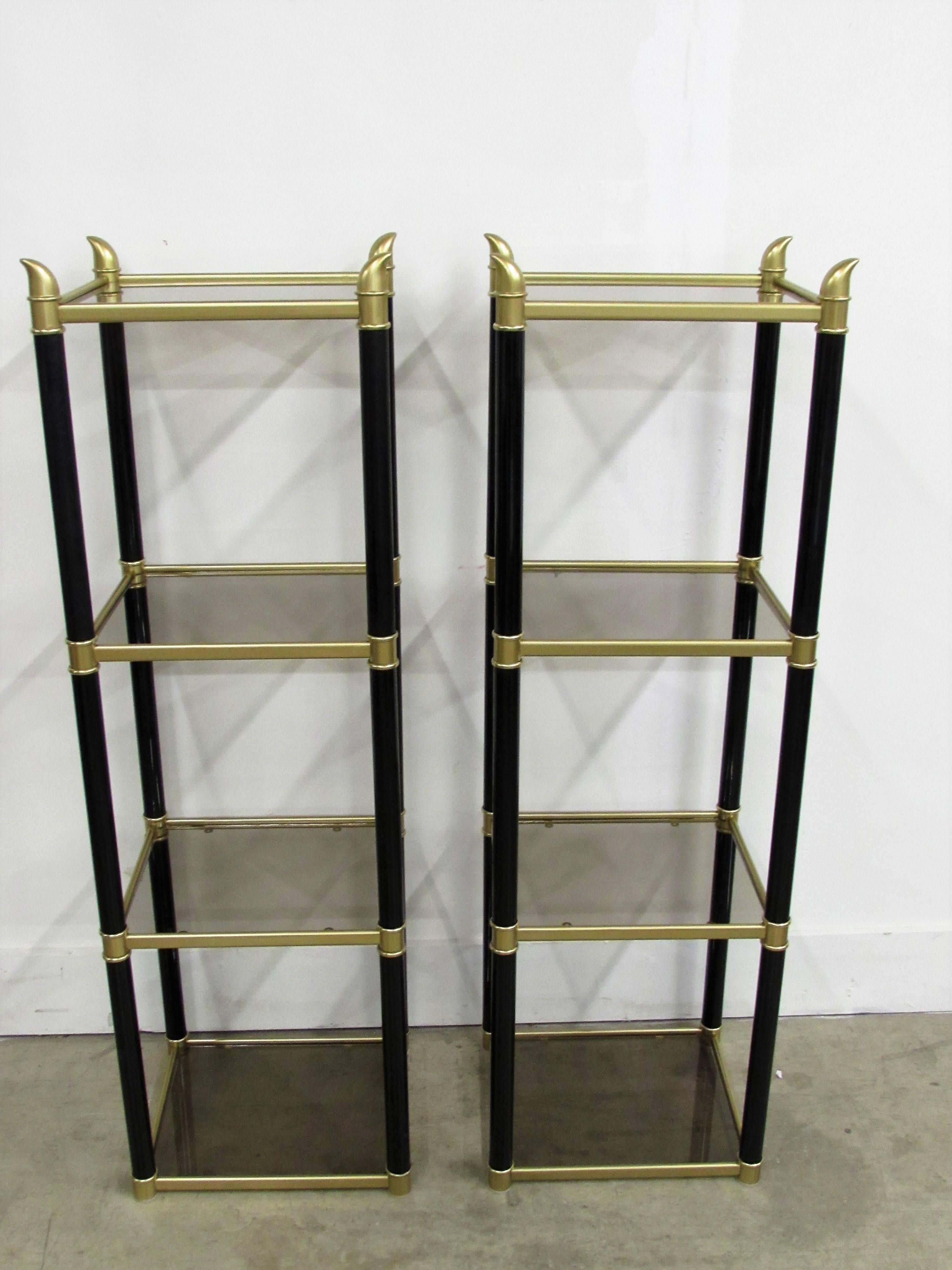 Pair of chinoiserie metal black and gold étagerés with smoked glass on four shelves topped with a faux buffalo horns on each corner.