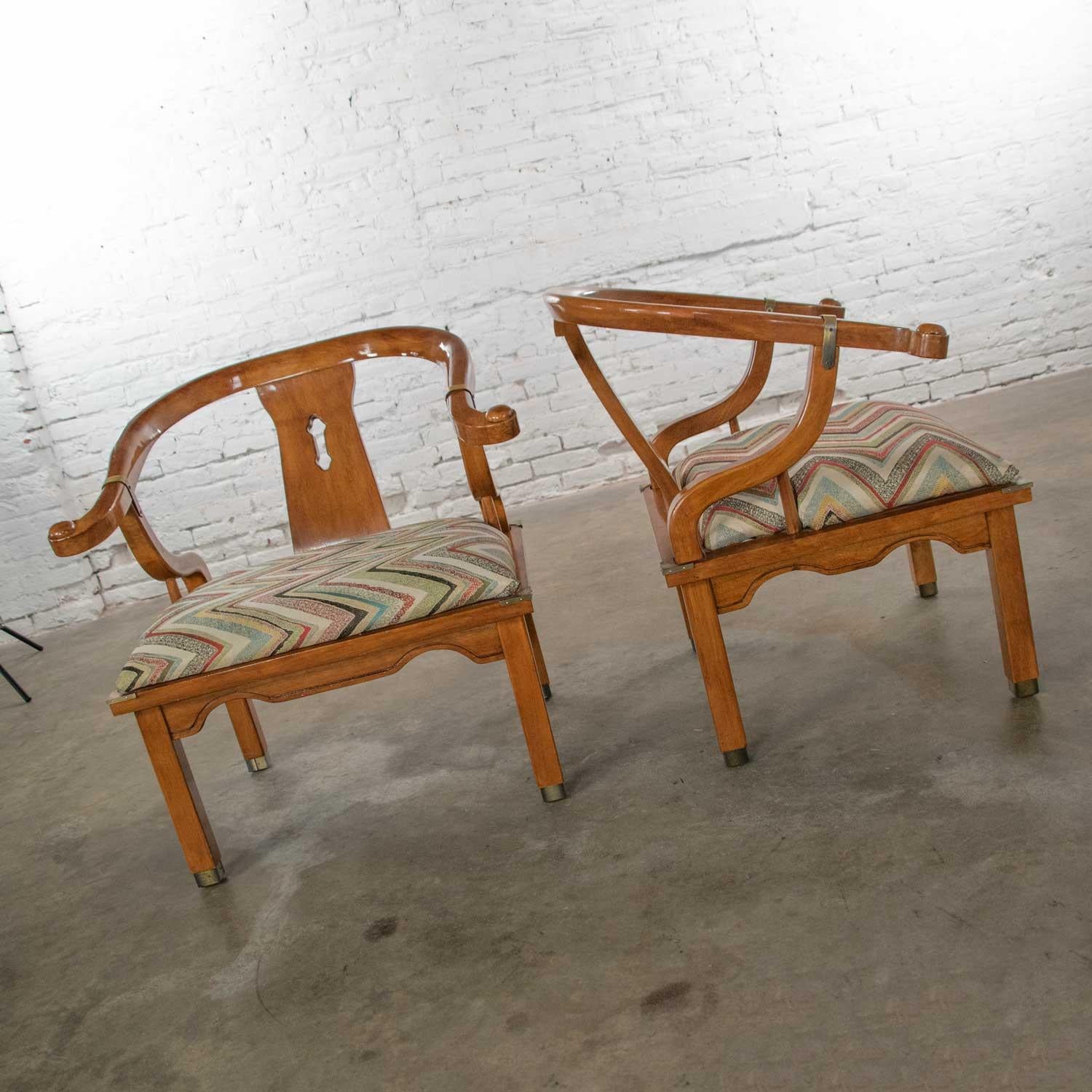 Marvelous pair of chinoiserie Ming style yoke back lounge chairs with a little Hollywood Regency pizzazz attributed to Schnadig Furniture International. Comprised of gorgeous wood, brass, and flame stitch fabric. Beautiful vintage condition with