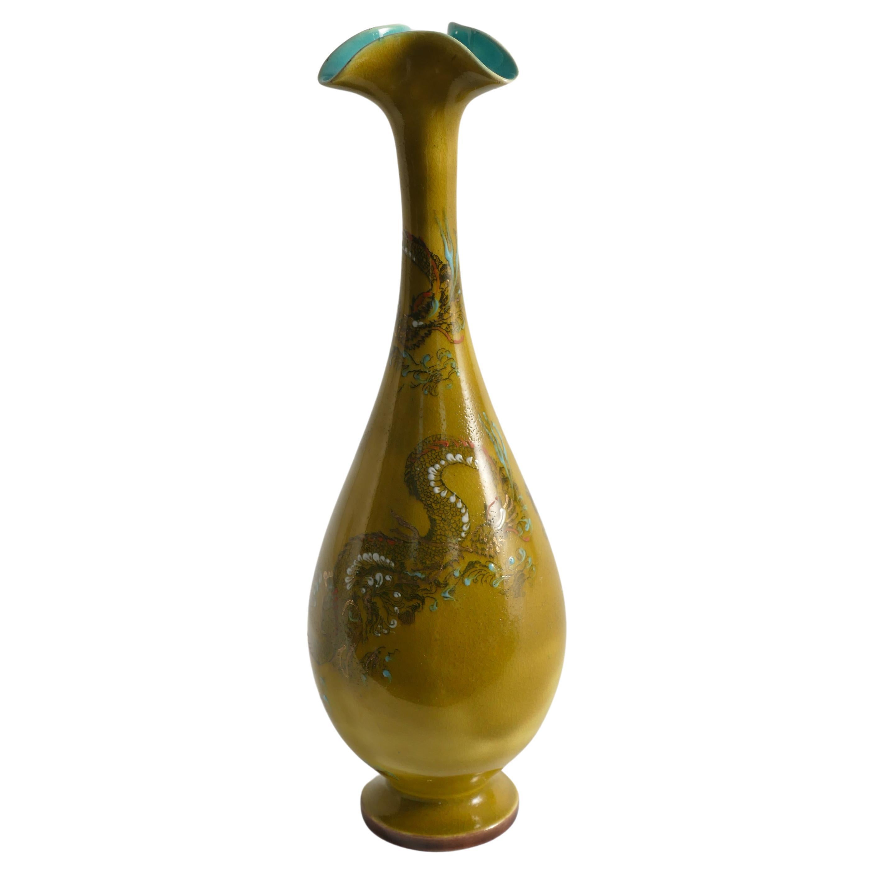Elegantly adorned with intricate chinoiserie dragon detailing, this ceramic ochre yellow vase from Lambeth Doulton Faience exudes timeless charm and exquisite craftsmanship. Two meticulously painted dragons grace the surface, each scale meticulously