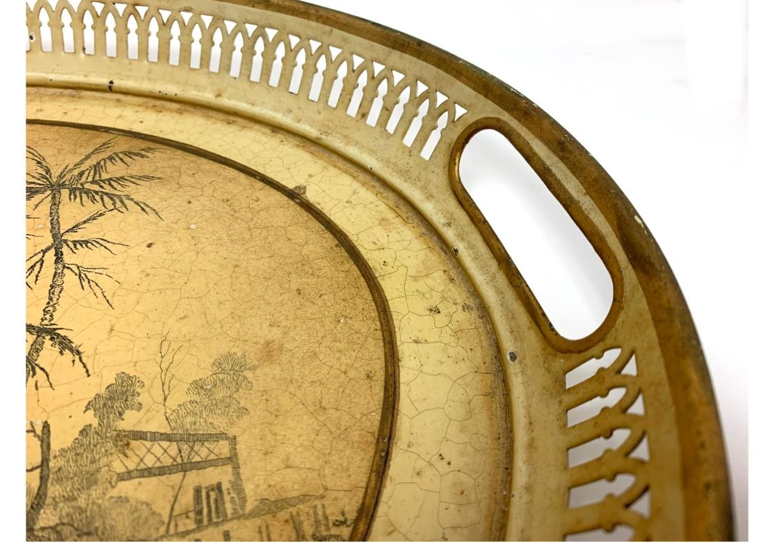Fin 19e/début 20e siècle Plateau ovale en tole jaune avec bordure réticulée, deux poignées, bordure dorée, pâte Chinoiserie au centre, fond floqué. L'image représente une scène de rivière exotique avec une hutte extravagante, des messieurs