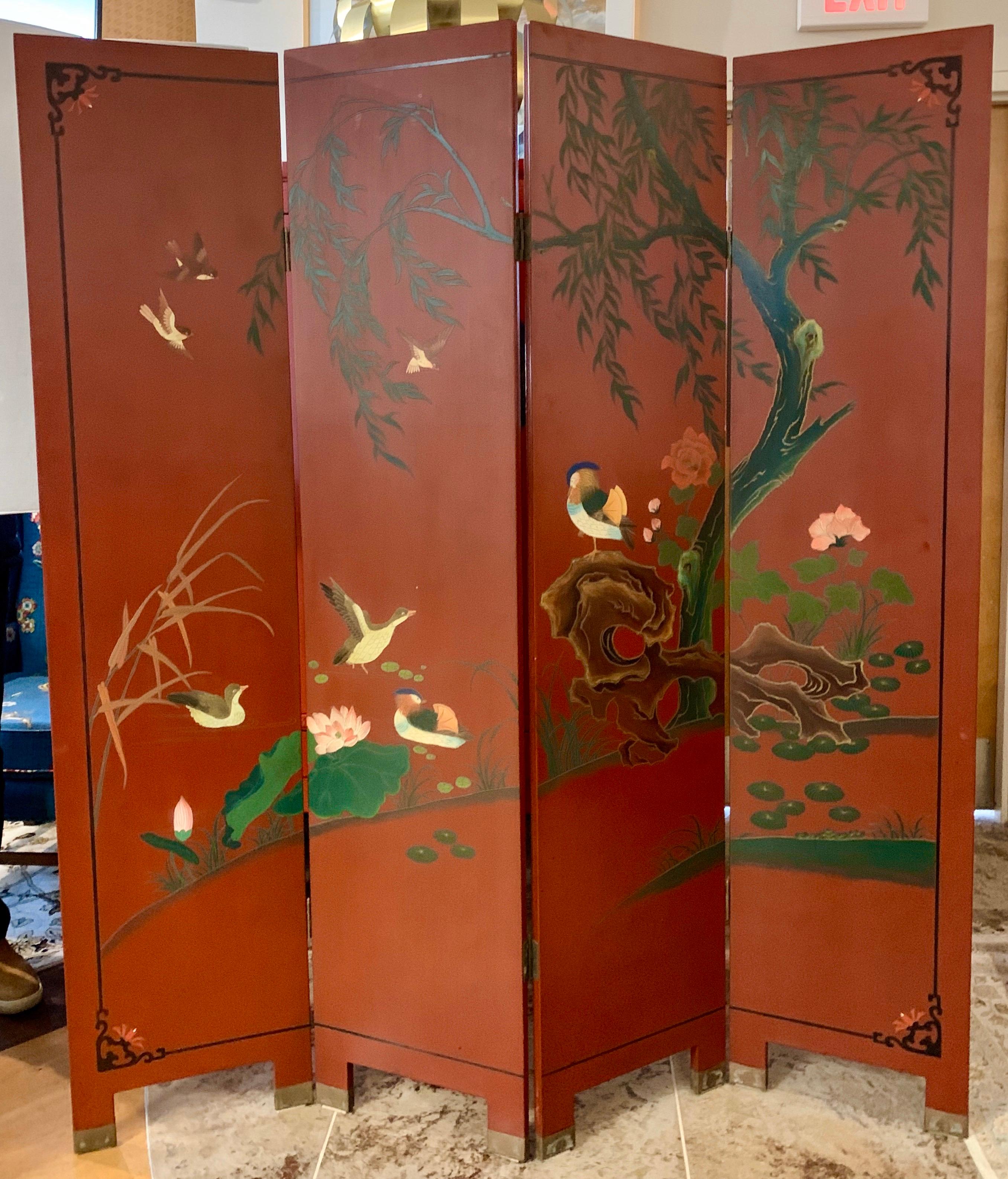 Asian chinoiserie wood screen in red lacquer with a beautiful hand painted motif of birds and flowers, mid-20th century screen composed of four panels supported on brass capped feet. Back also has hand painted scenery. Great scale with each of the