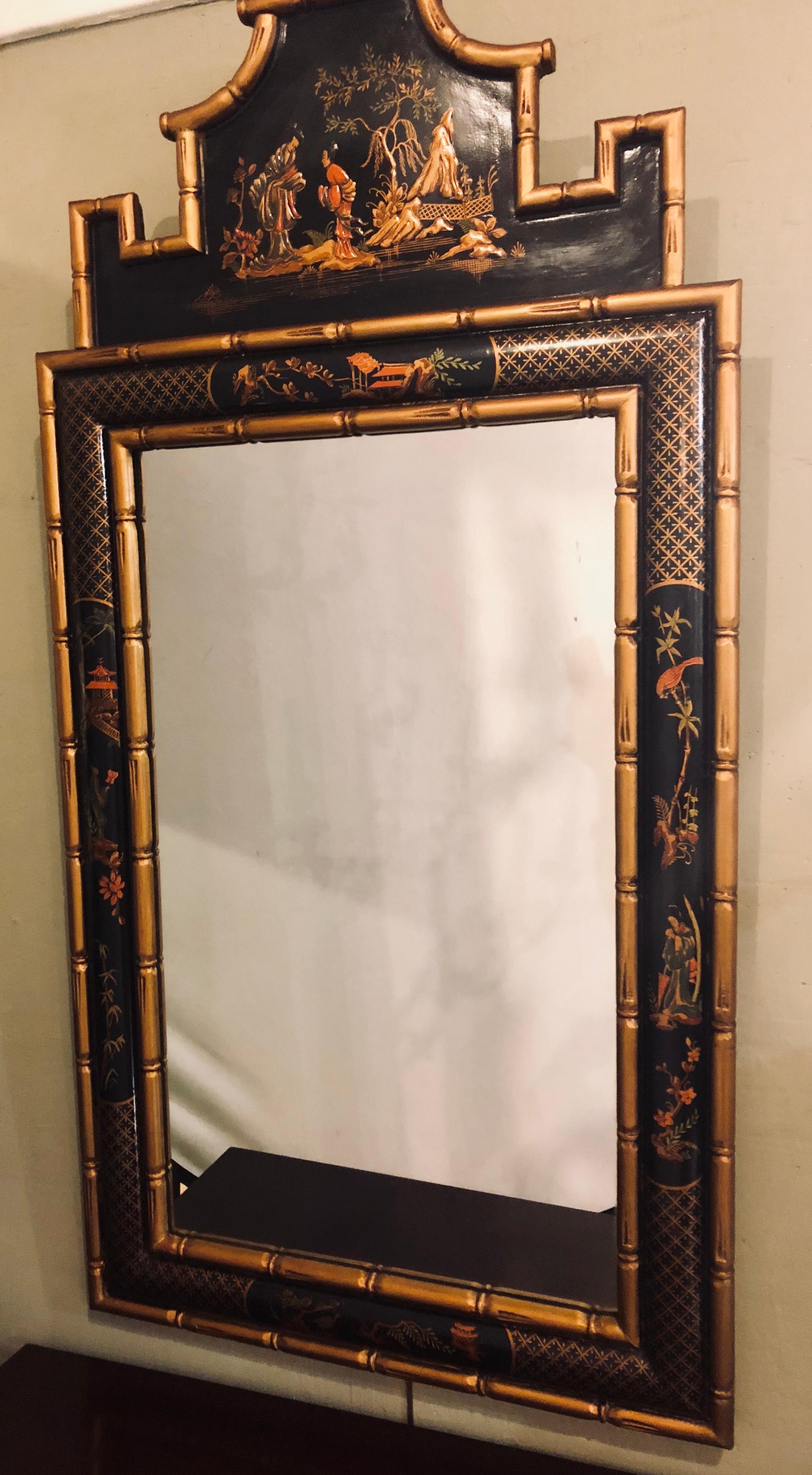 A chinoiserie style bamboo frame wall or console mirror. This Hollywood Regency Era wall mirror depicts the ancient era of Japanning at its finest. The framed faux bamboo design flanking a center border depicting multiple raised figures both indoor