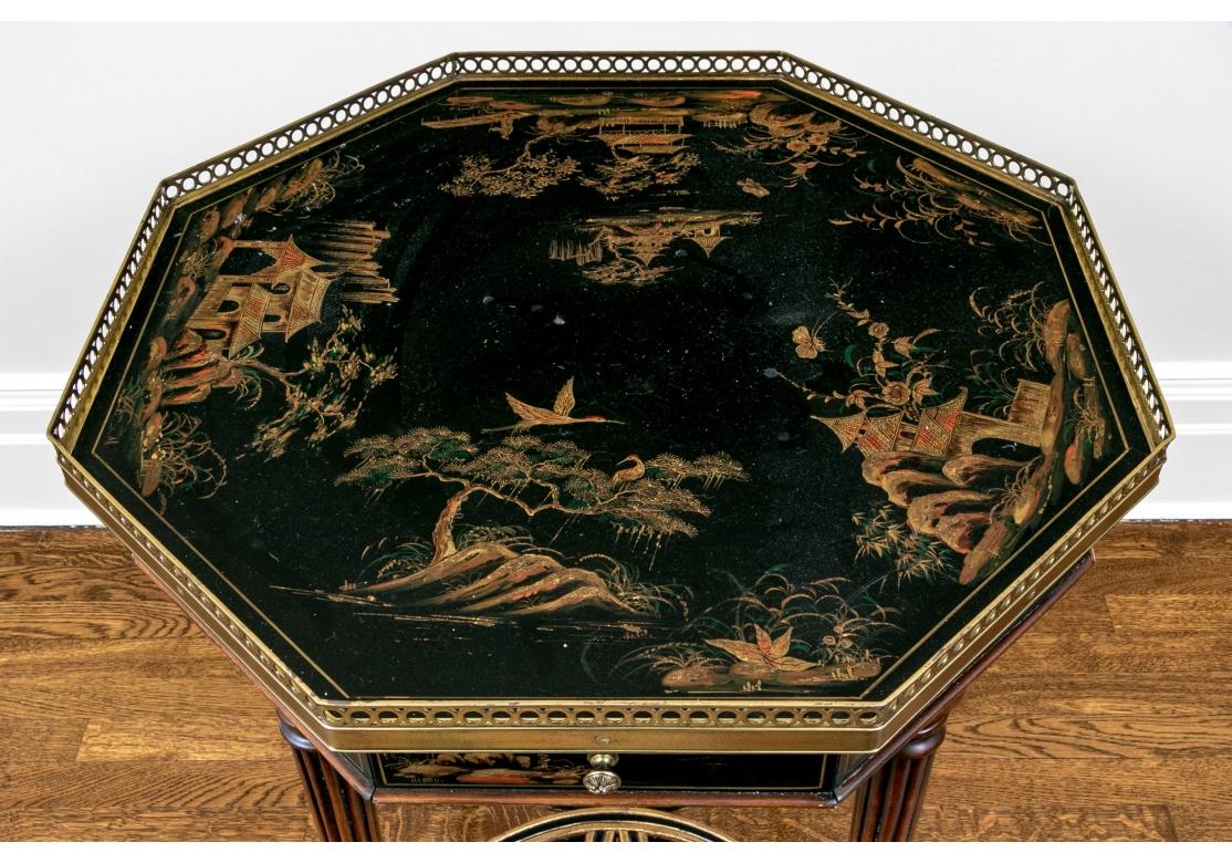 Chinoiserie octagonal accent table with fine form and color. Features a classic black lacquer and gilt design with scenes of Asian architecture and natural landscapes decorating an octagonal top surrounded by a pierced brass gallery. The apron is
