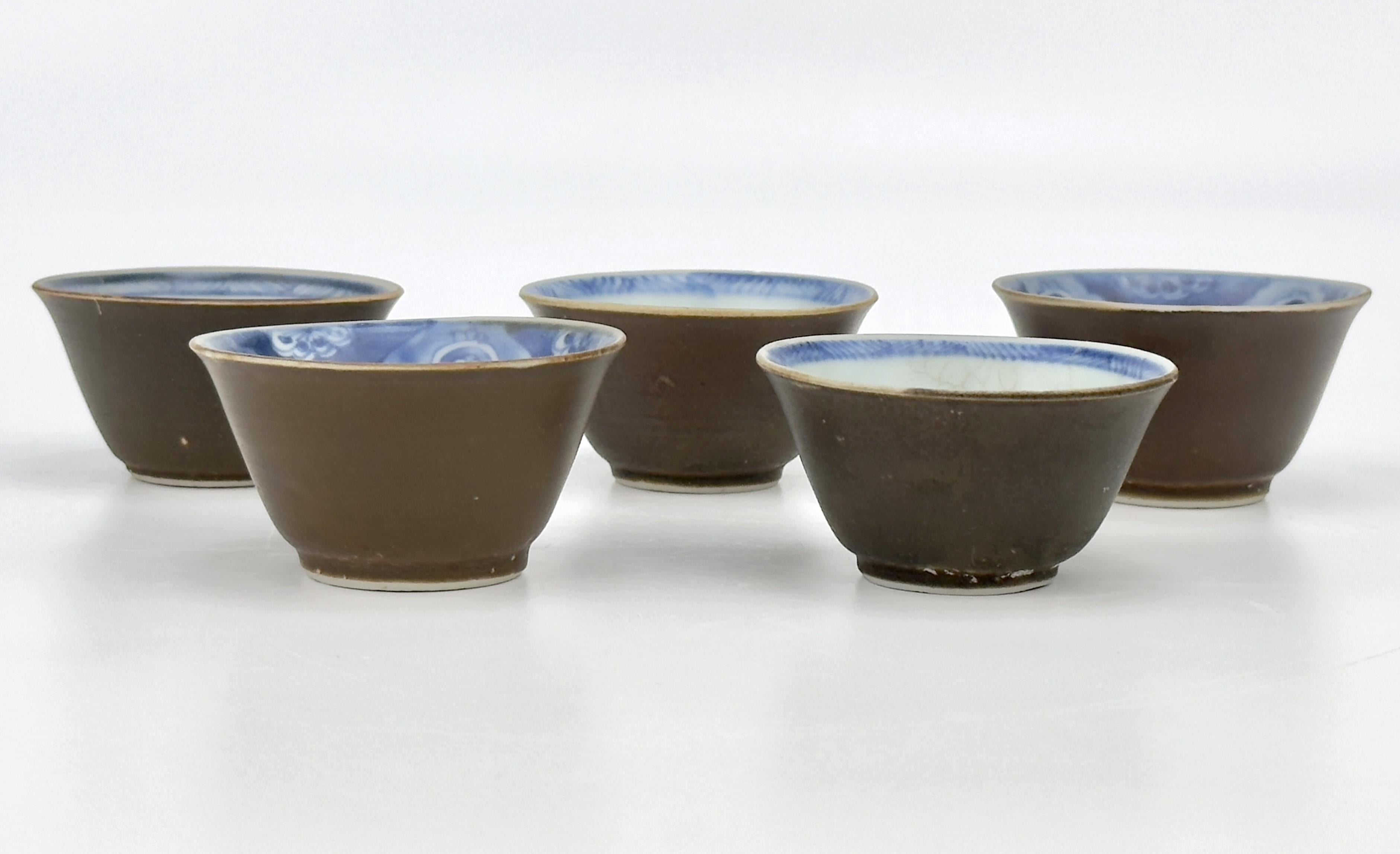 L'intérieur des coupes est orné de motifs complexes inspirés de la nature, tels que des fleurs, des arbres et des poissons. Elles sont habilement disposées pour créer un point focal à la base de chaque tasse, donnant à chaque pièce une narration