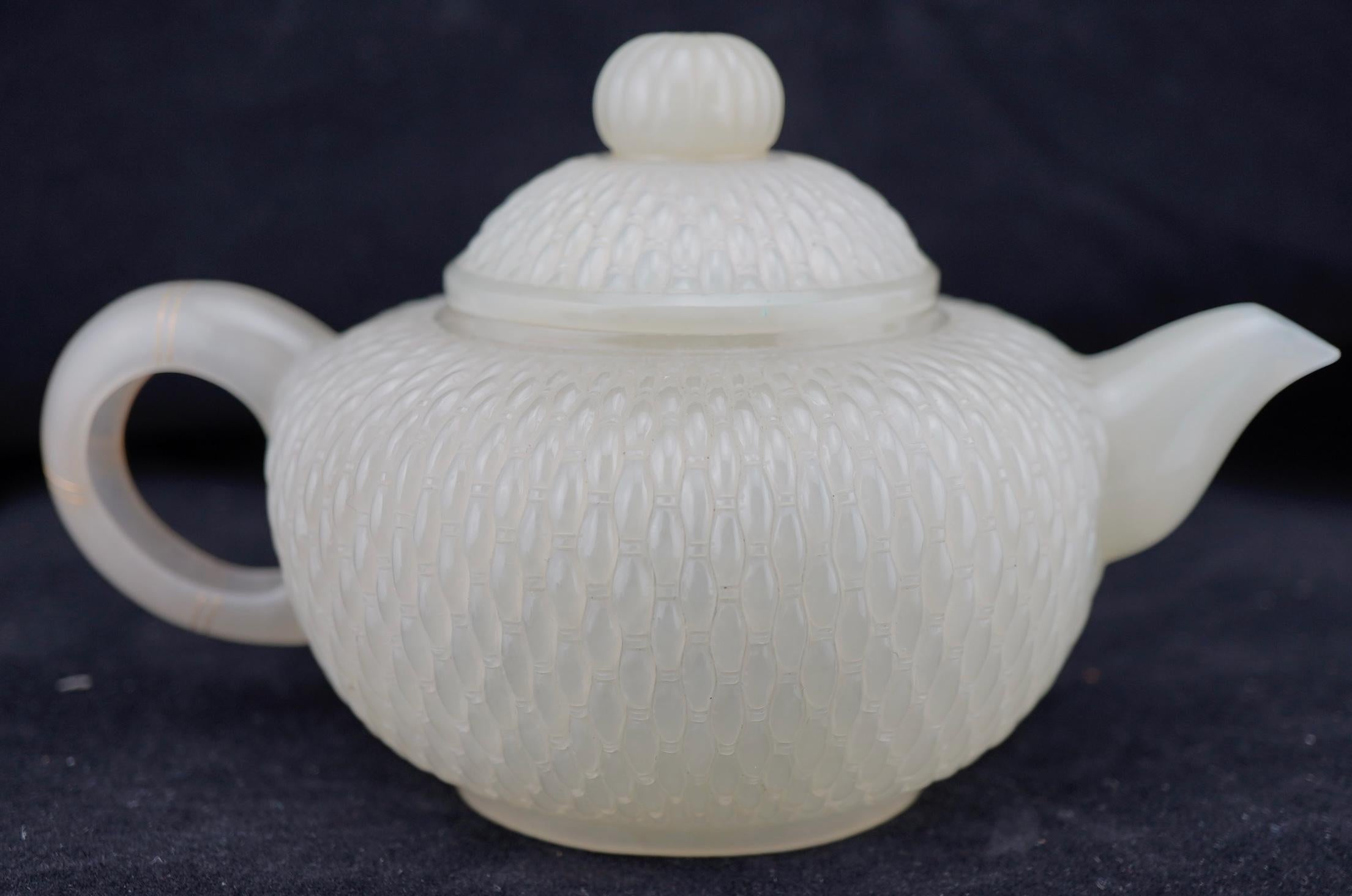 Chinese nephrite jade teapot compressed globular form, with S-shaped spout and C-shaped handle. The body decorated with hand carved fine basketweave pattern. The domed cover with a bud-form finial, the handle with three double rings inlaid in gold,