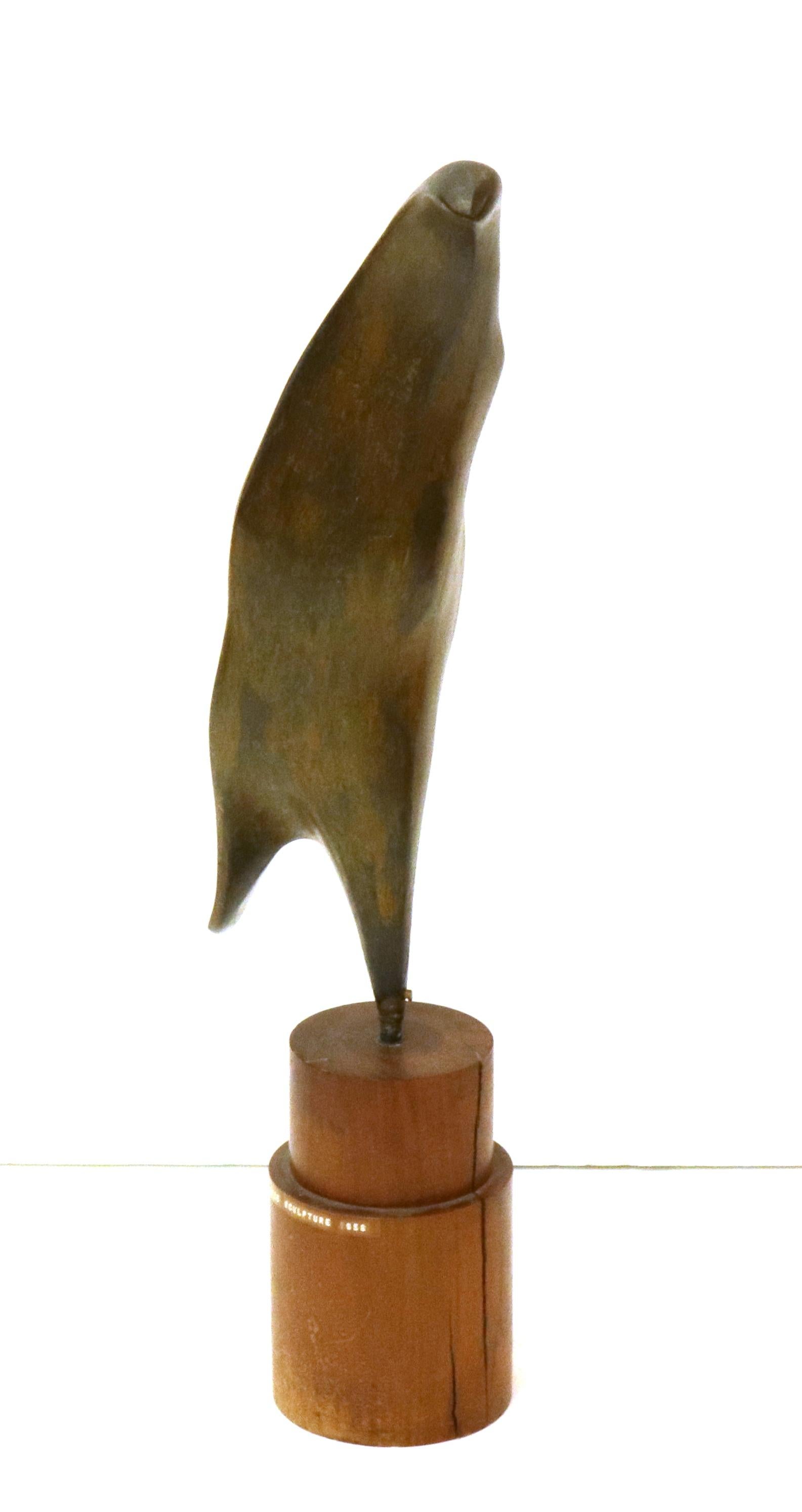Italian Mid-Century Modern abstract bronze sculpture depicting a penguin, made by Chio (b. 1917) in 1958. The green patina bronze is mounted on a cylindrical wooden base with label informing on artist name, title and date (1958). 
The piece is in