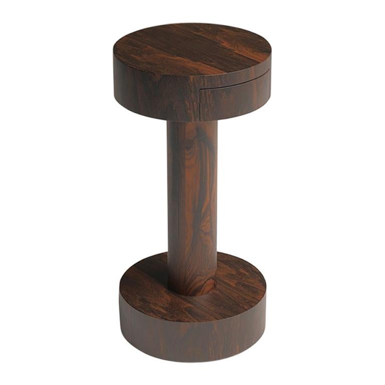 Chiodino est une table d'appoint ronde avec un tiroir, en bois précieux de ziricote ; conçue par Aldo
Cibic. Une petite table aux proportions inattendues en bois fin et foncé aux veines marquées,
une forme emblématique qui s'adapte à tous les