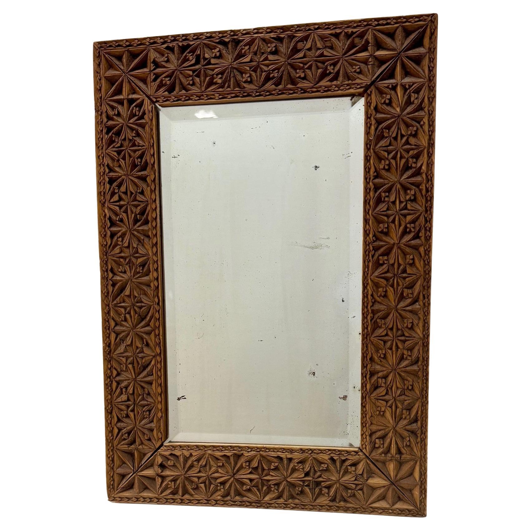 This is an outstanding example of chip carving. It is subtly detailed and imaginative, both geometric and tendrilled, the flowing plant forms and angular framing coexist in harmony with each other. The mirror plate is bevelled. The air-burn suggests