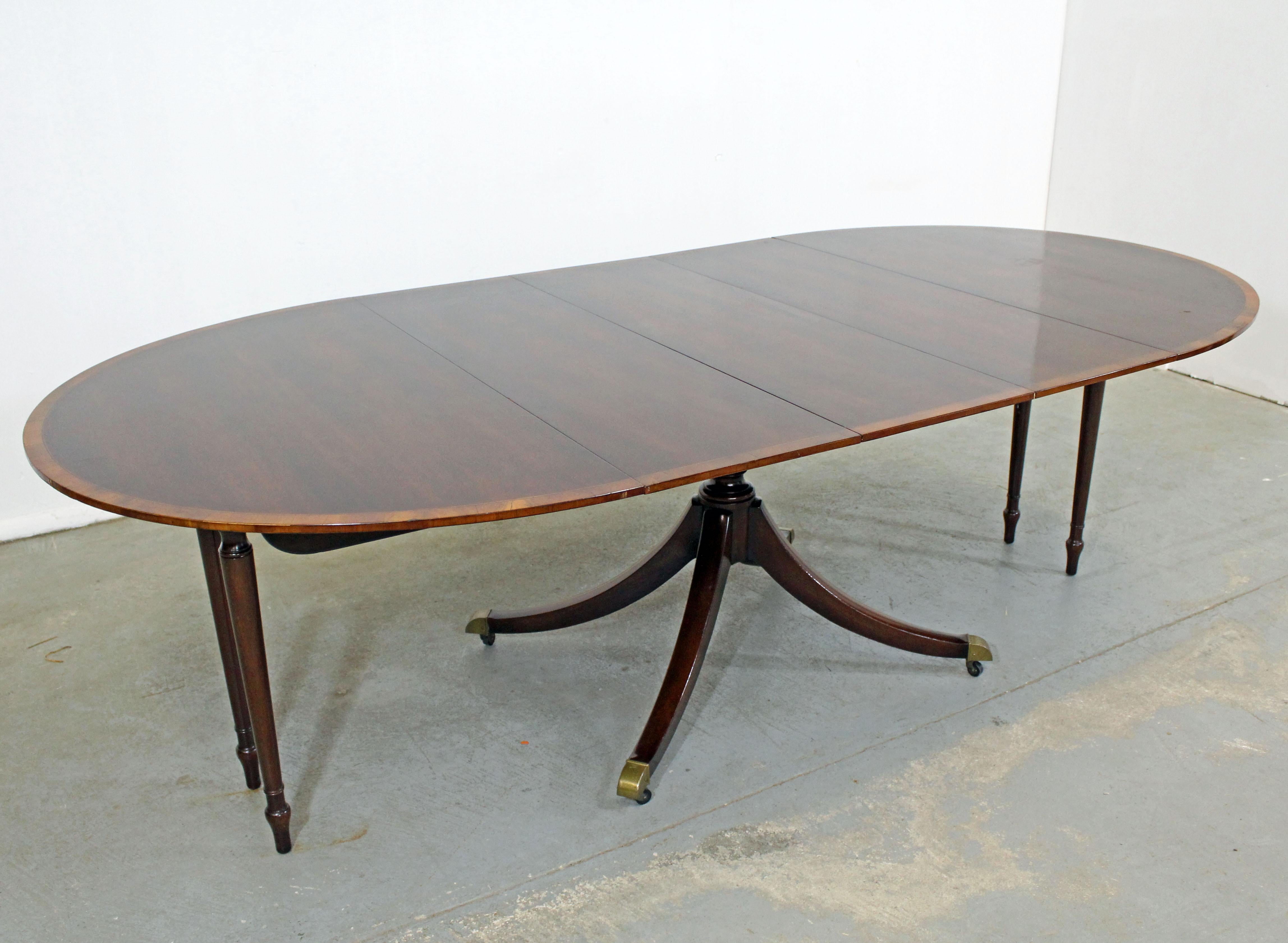 Offered is a beautiful Chippendale extendable cherry dining table with three table leaves. It is made of cherry with banded mahogany and features a pedestal base and legs that come out when fully extended. It is in excellent condition for its age,