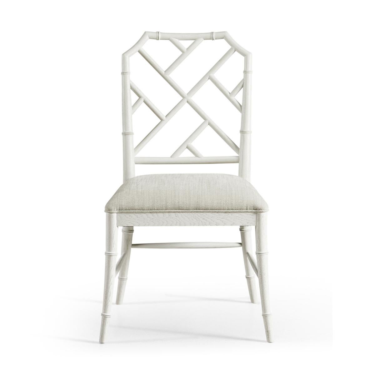 Chippendale bamboo dining chair, this timeless geometric design lattice back bamboo formed dining side chair is finished in dry chalk white with light distressing. Upholstered in earthy oatmeal performance fabric, the chairs will add comfort and