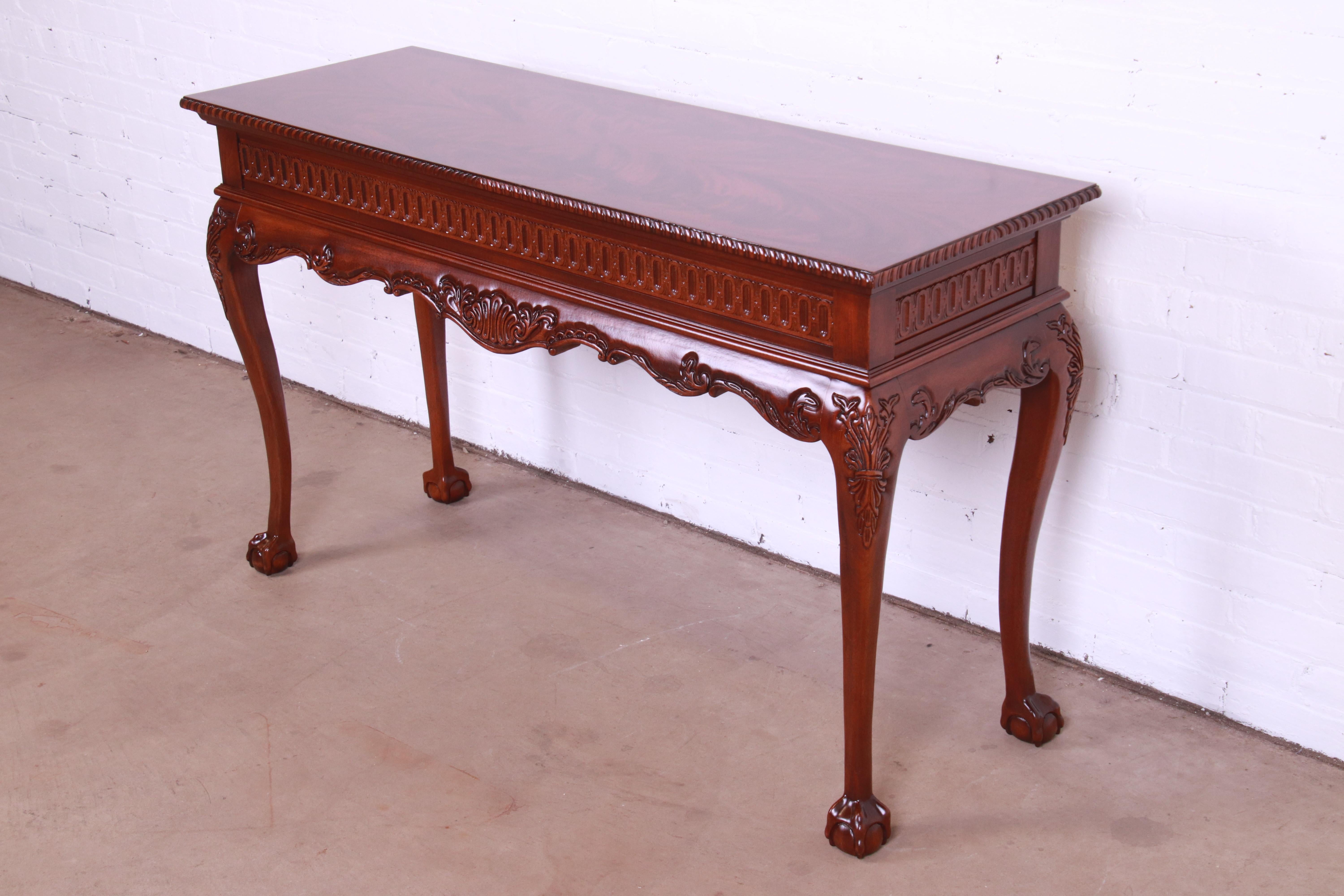 A gorgeous Chippendale style console or sofa table with ball and claw feet

In the manner of Baker Furniture

USA, Circa 1980s

Carved solid mahogany, with book-matched flame mahogany top.

Measures: 52