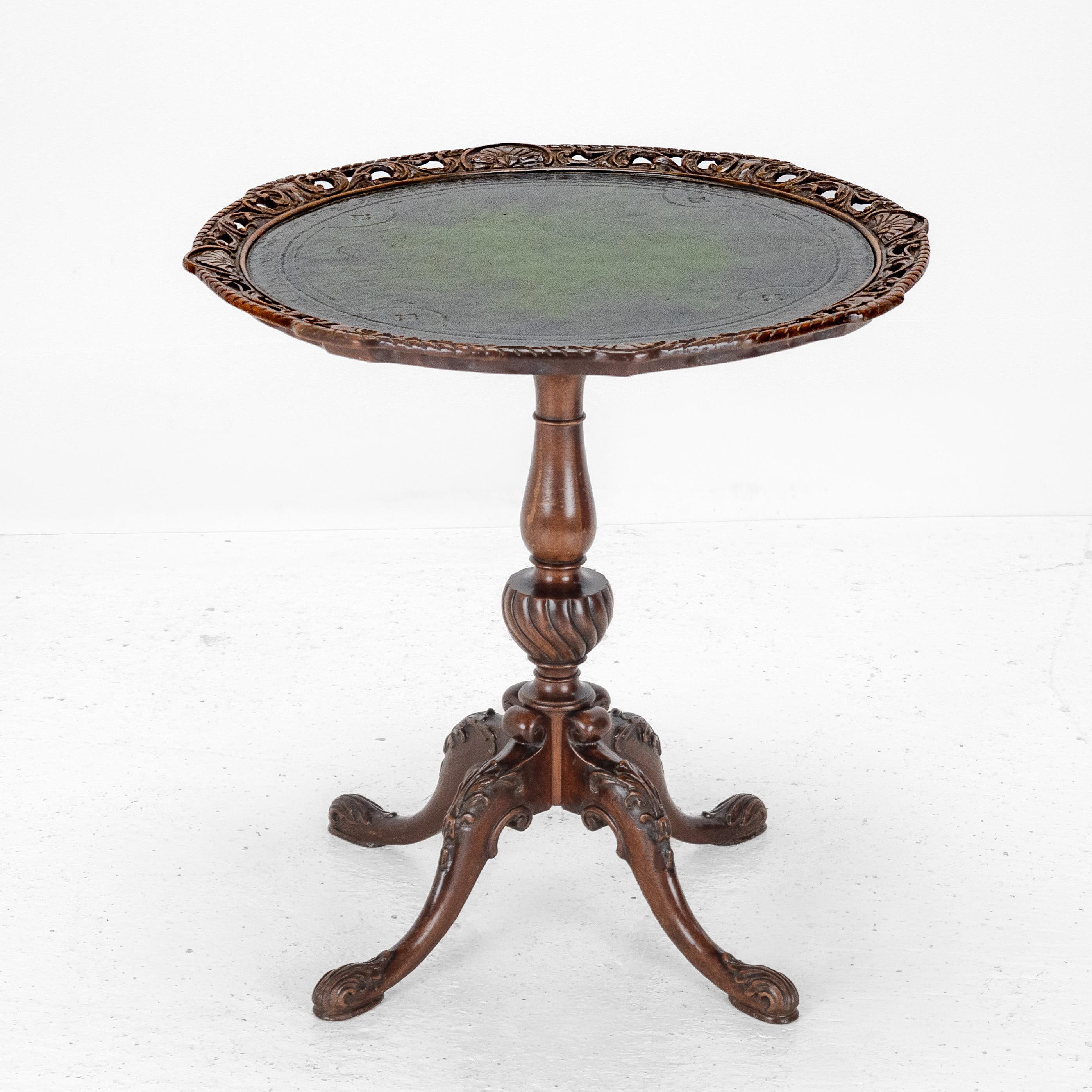 Chippendale Style Carved Walnut with Leather Top Table

A fine late 19th-century walnut wine or occasional table in the Chippendale manner. The circular top features a beautifully carved pierced gallery with foliate and scroll motifs, surrounding an