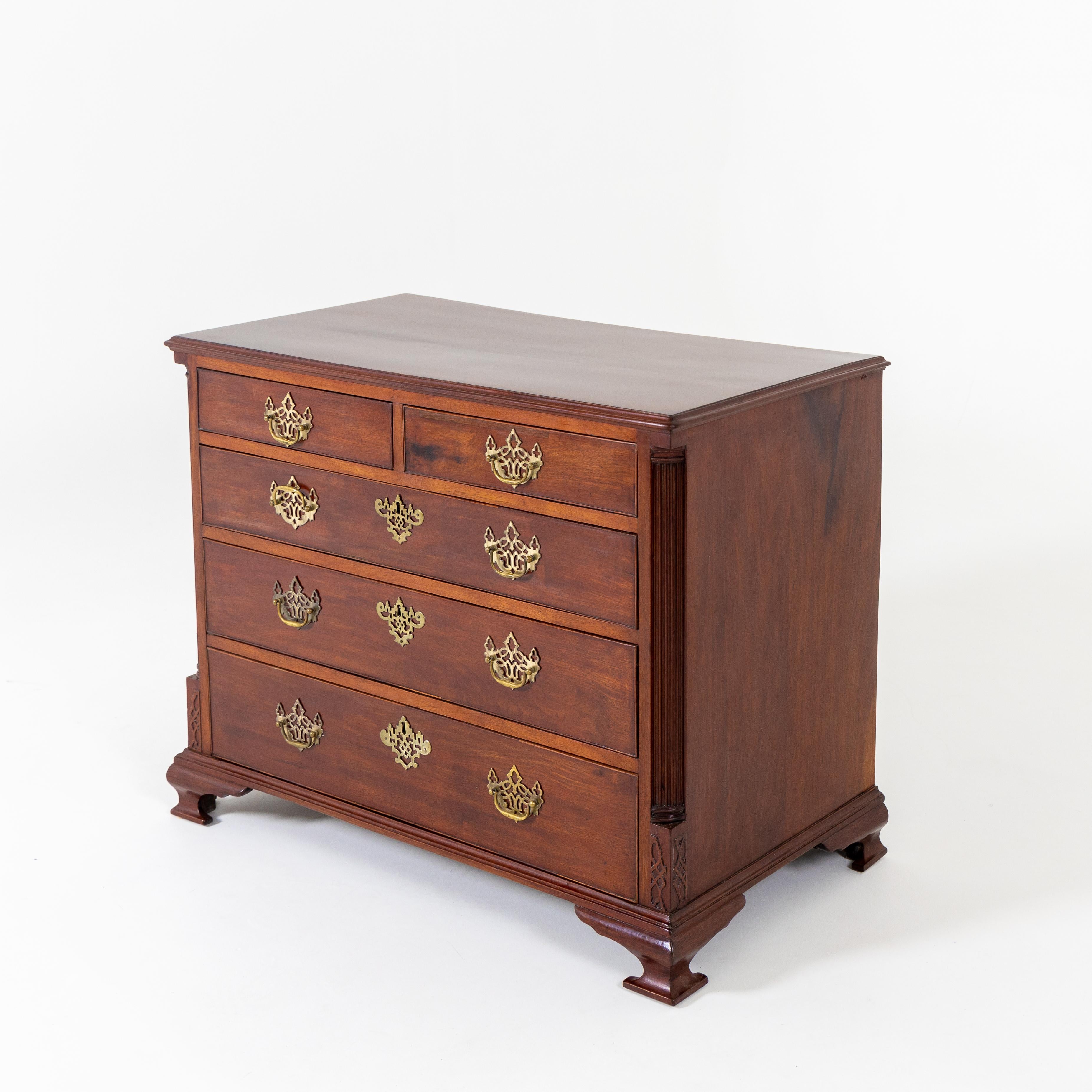 Chippendale chest of drawers in mahogany, standing on flared architrave feet. The rectilinear corpus is provided with three full-length drawers and two smaller ones. The corners are accented by fluted quarter columns and banding in relief. The
