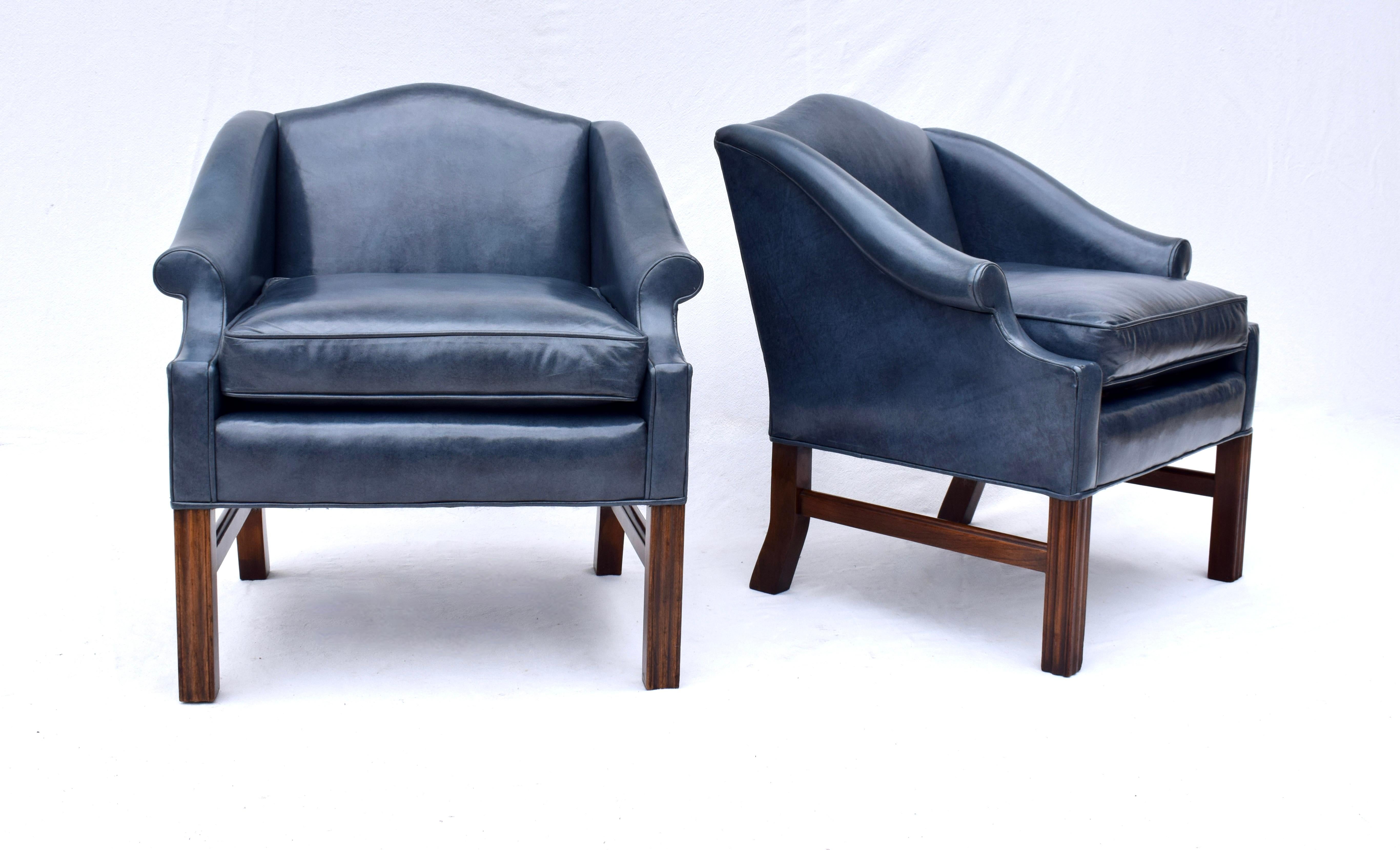 A pair of blue leather Chippendale Chesterfield style club chairs by Harden Furniture Company featuring camel back forms with scroll arms and solid Mahogany bases. We love everything about these comfortable mid sized chairs. Seats: 19