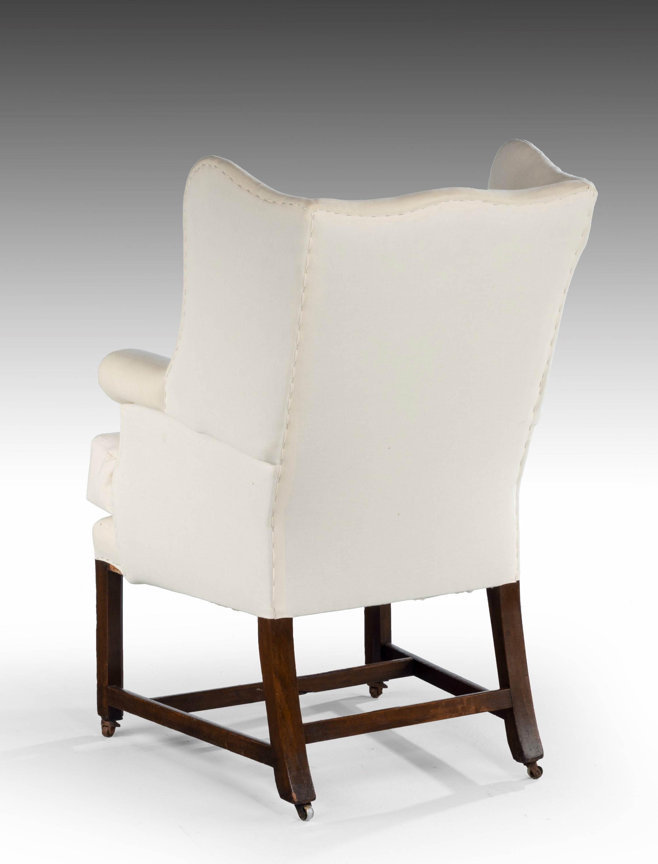 A mahogany wing chair of Chippendale design of quite small proportions, the shaped wings over rolled arms on square chamfered supports with an H stretcher. Now reupholstered in white cambric.

Seat height = 21.5 inches.
