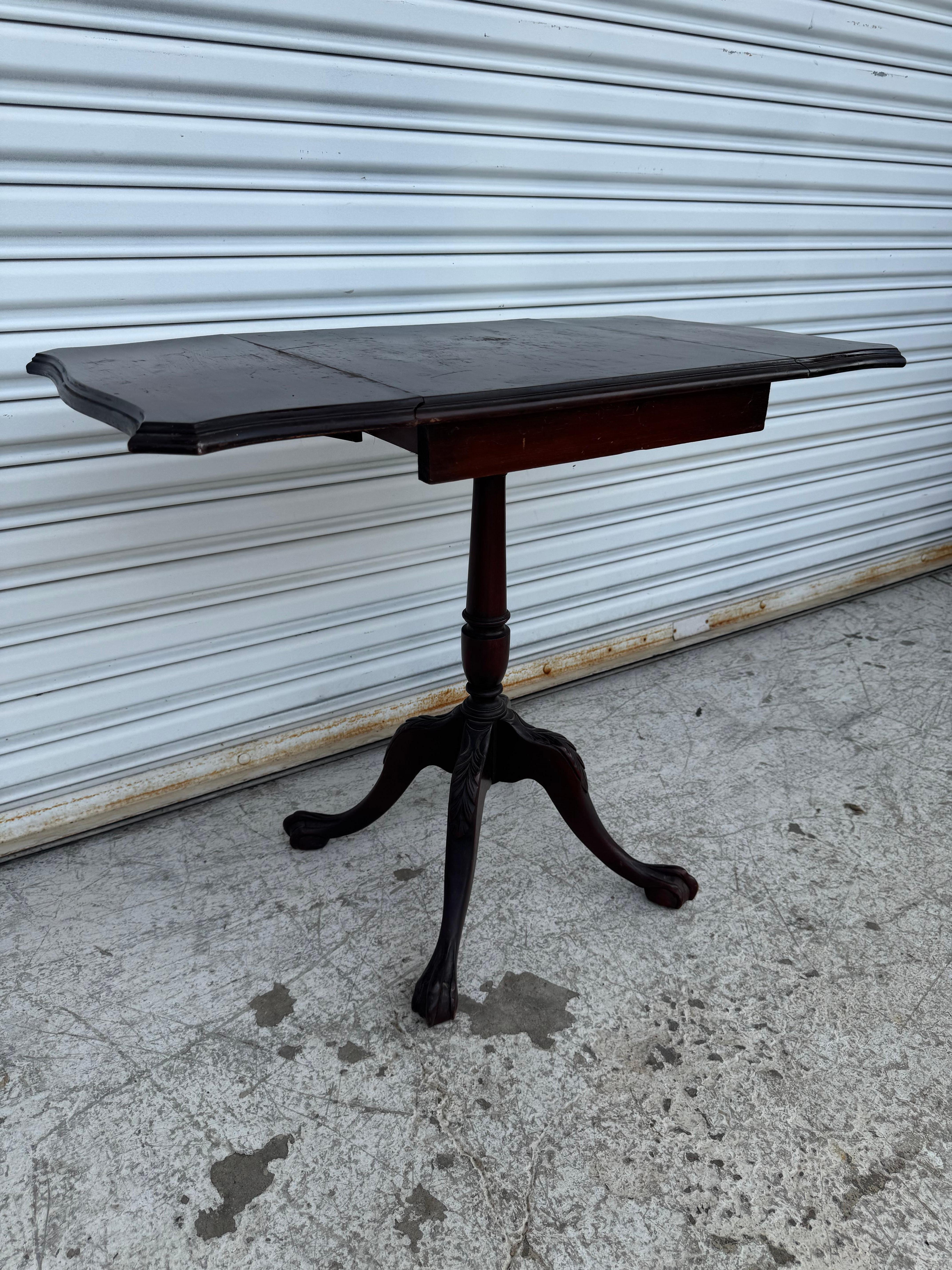This elegant Chippendale Drop Leaf Table showcases timeless craftsmanship with its rich mahogany finish and carved cabriole legs ending in classic claw-and-ball feet. Featuring a traditional drop-leaf design, this versatile piece measures 16” x 16”