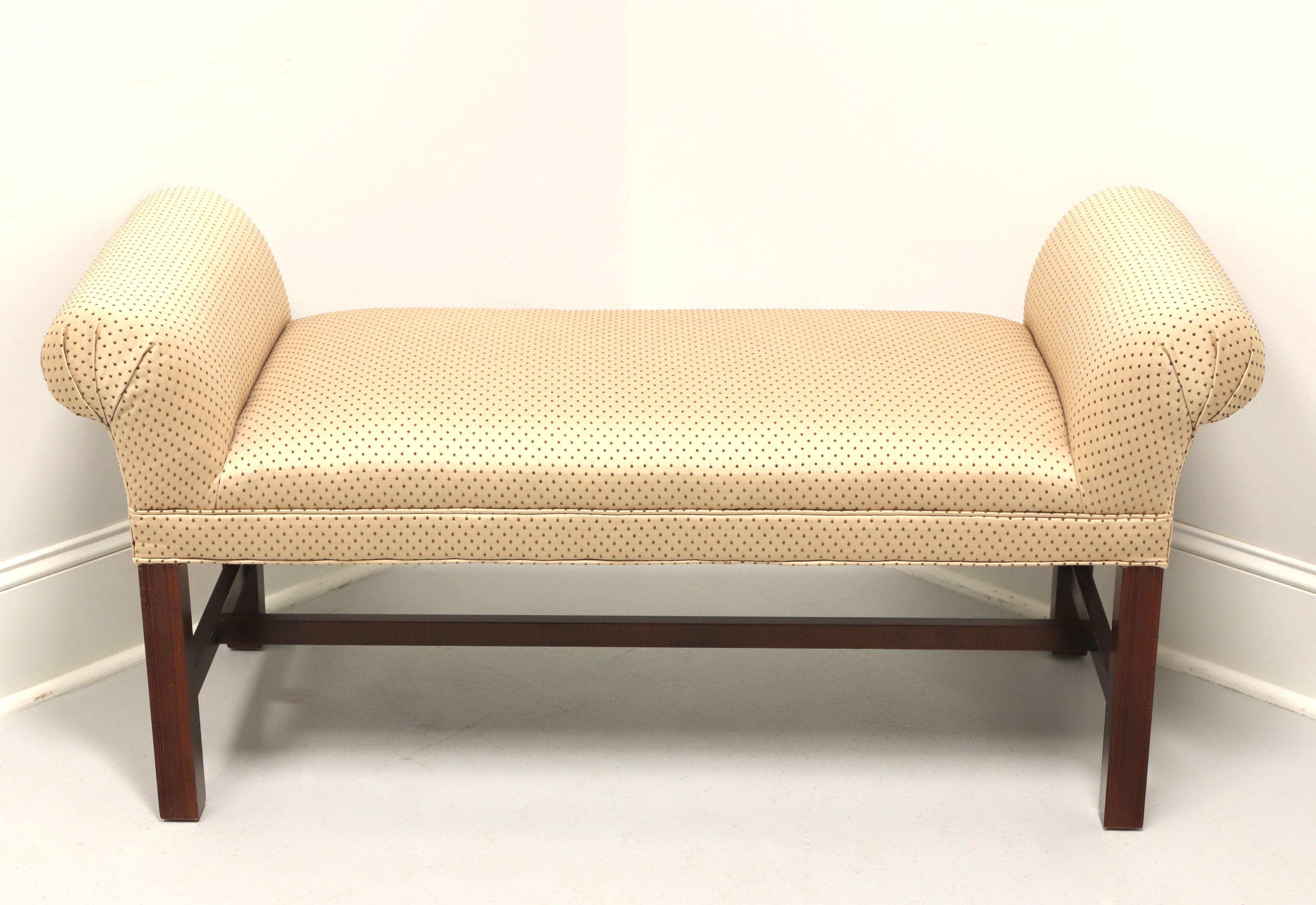 A scroll arm upholstered bench in the Chippendale style, unbranded. Mahogany frame, scroll arms, gold with burgundy dots colored fabric upholstery and straight legs with stretchers. Made in the USA, in the late 20th Century and re-upholstered in the