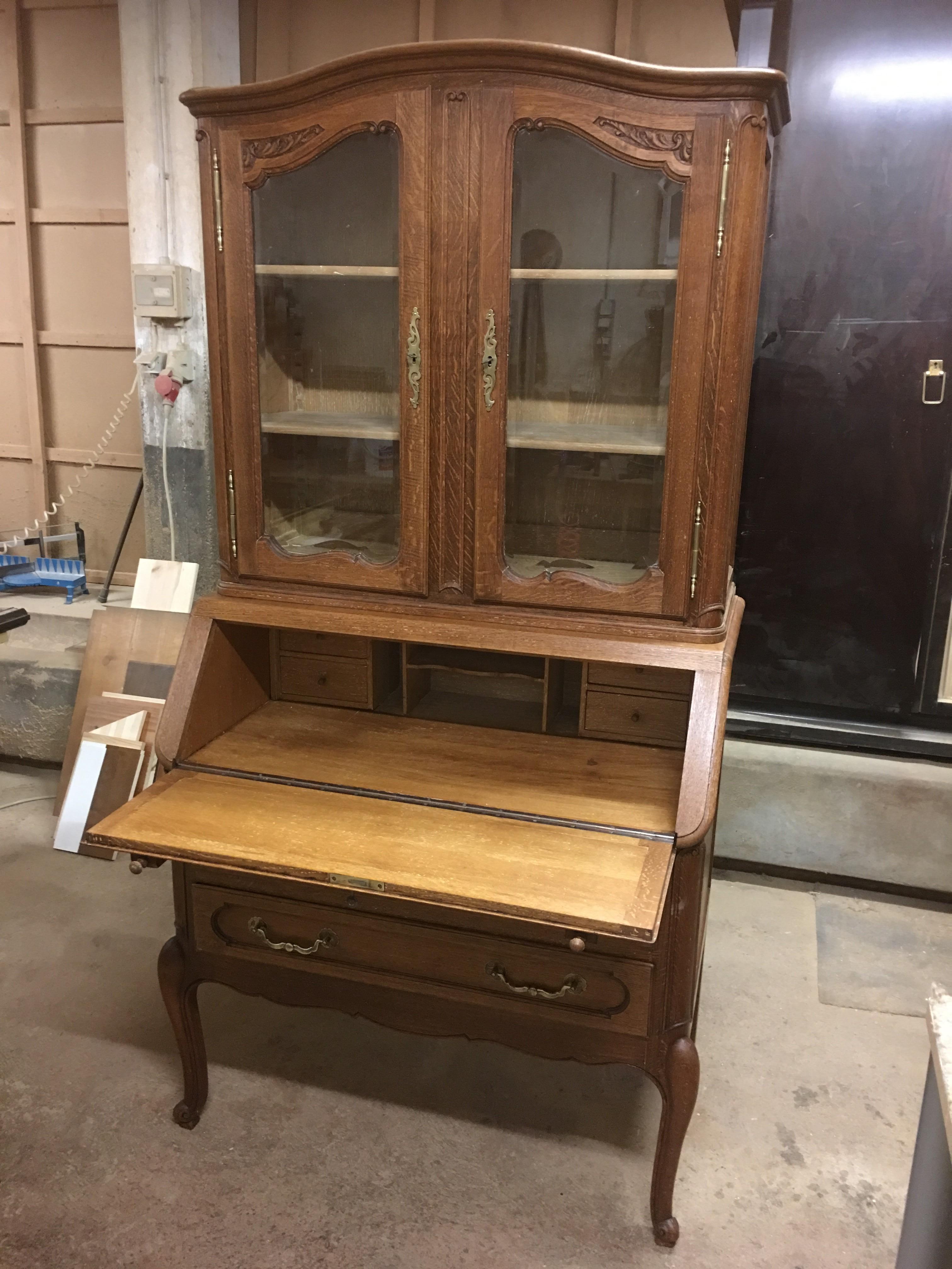 This is a Chippendale oakwood secretary with hinged writing tablet and a glass showcase perfect for displaying your items. Finest carvings decorate the dark oakwood. Shelves on adjustable toothed strips make the piece customizable and provide a