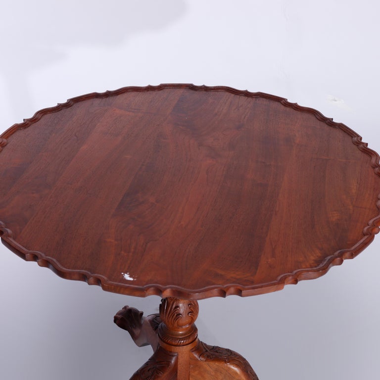 A Philadelphia Chippendale style tilt top table offers shaped top with raised lip over balustrade carved column having carved acanthus and raised on cabriole legs terminating in carved claw feet, 20th century 

Measures - 28.25''H x 35.75''W x