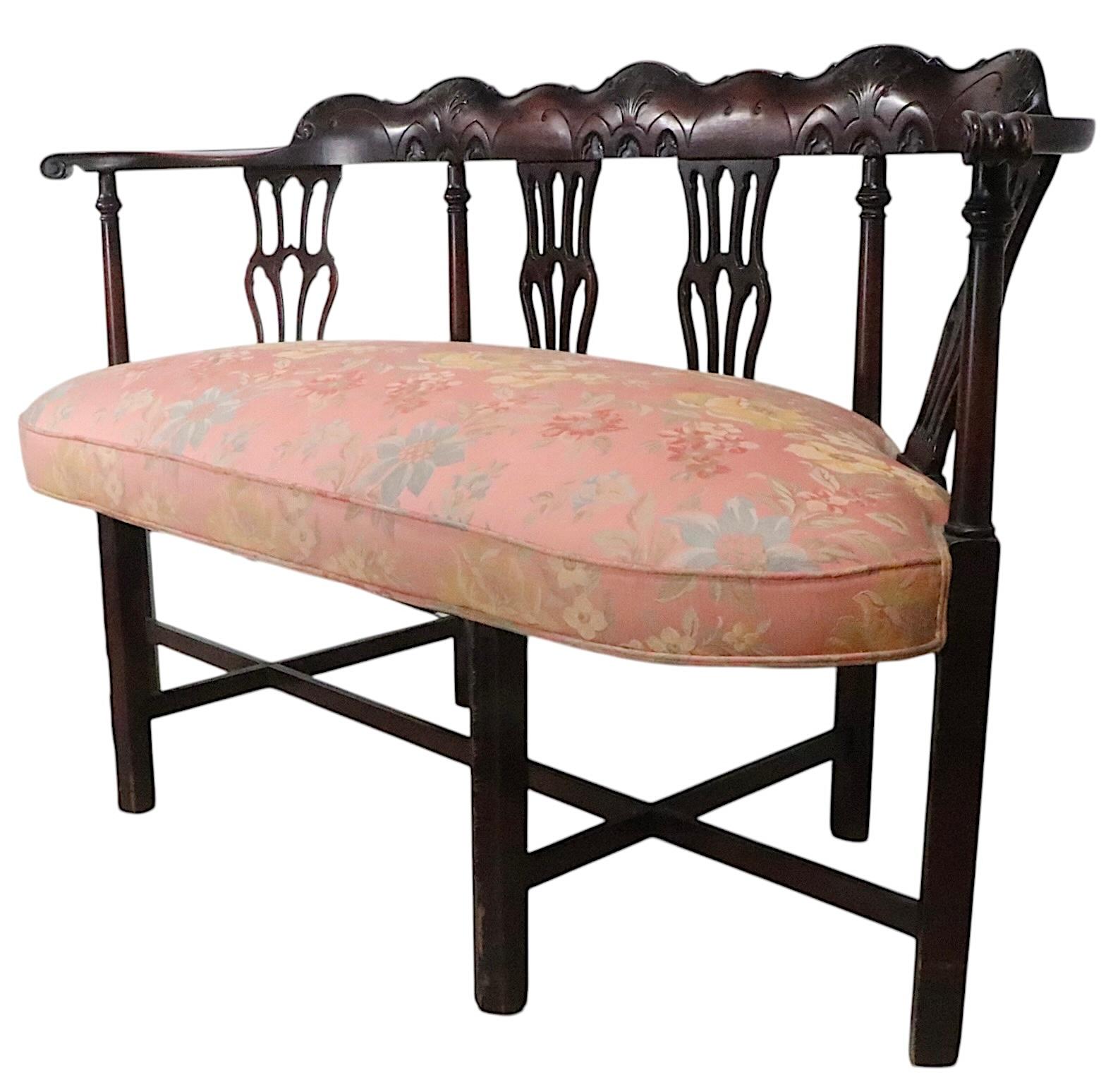 Charmante causeuse, canapé, de style néo-chippendale, avec un cadre incurvé en acajou et un plateau en bois de chêne.  siège rembourré en damas floral. Le cadre présente un support de base sculpté à la main, avec des panneaux de style chantourné.
