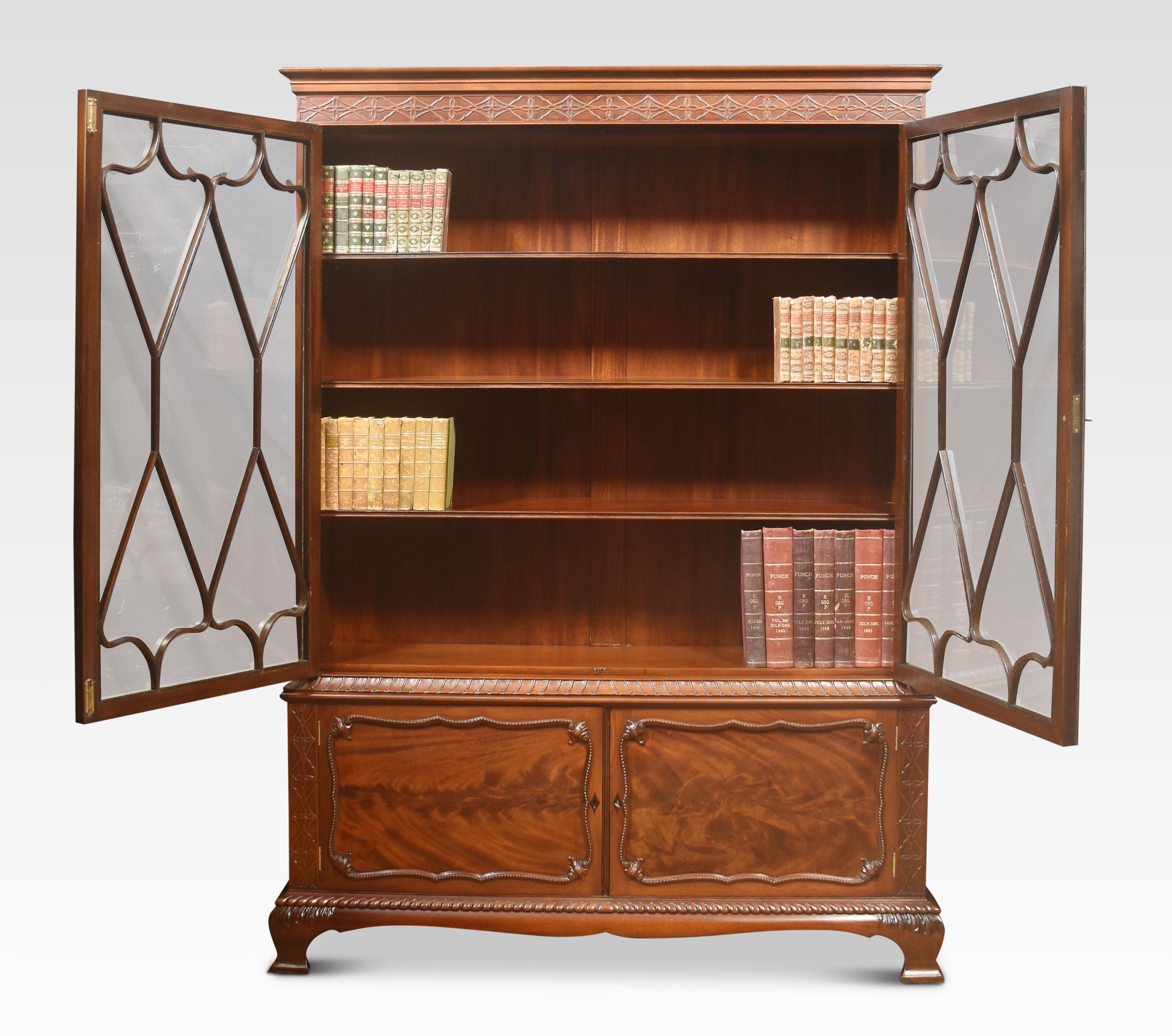 Chippendale Revival mahogany bookcase, the molded cornice, and blind fretwork frieze. Above two astragal glazed doors opening to reveal an adjustable shelved interior. The base section is fitted with two flame mahogany paneled doors, all raised up