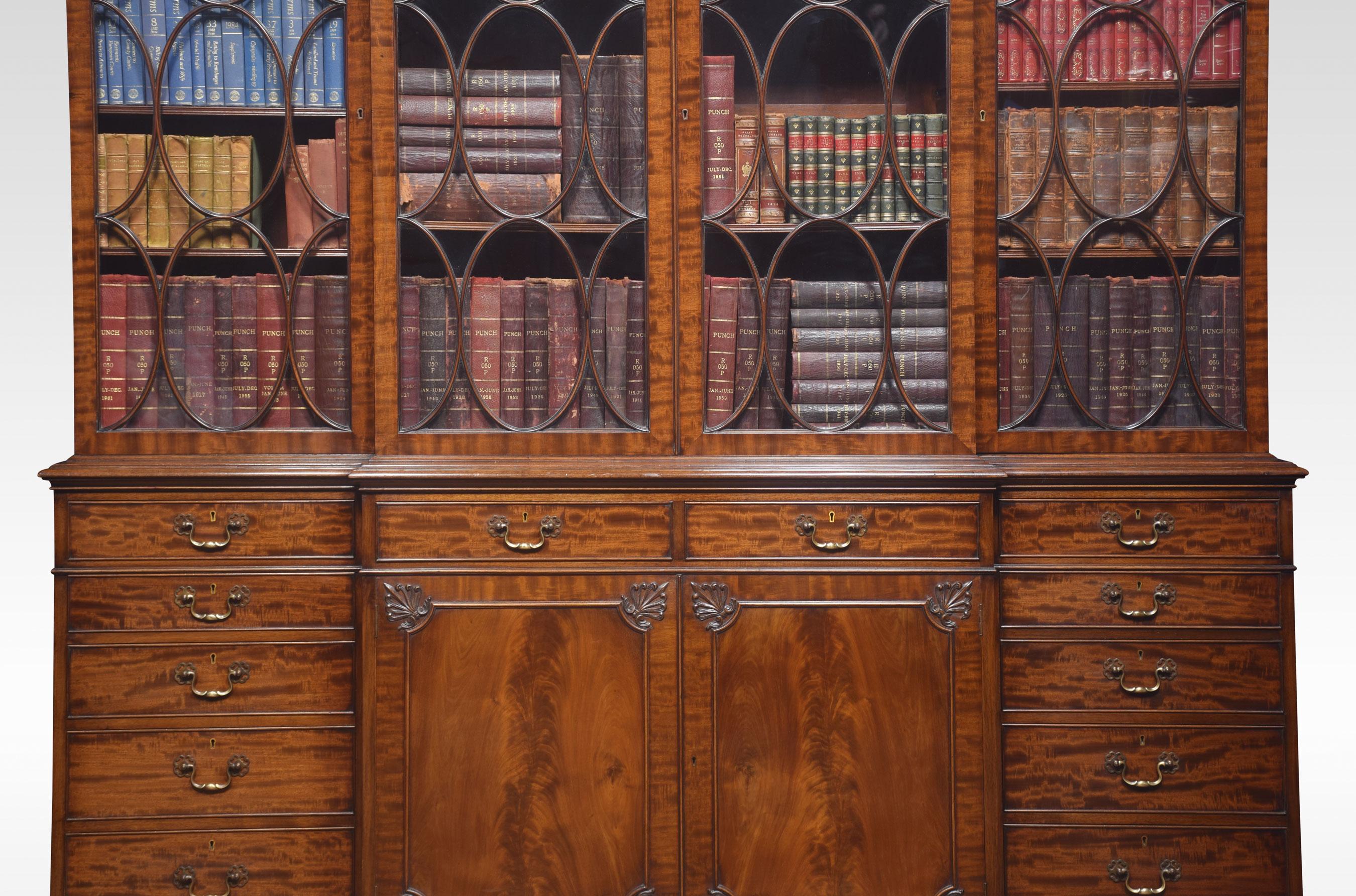 Chippendale Revival bookcase, the projecting breakfront molded cornice. Above four large astragal glazed doors opening to reveal an adjustable shelved interior. To the base section fitted with four frieze drawers with brass swan neck handles, above