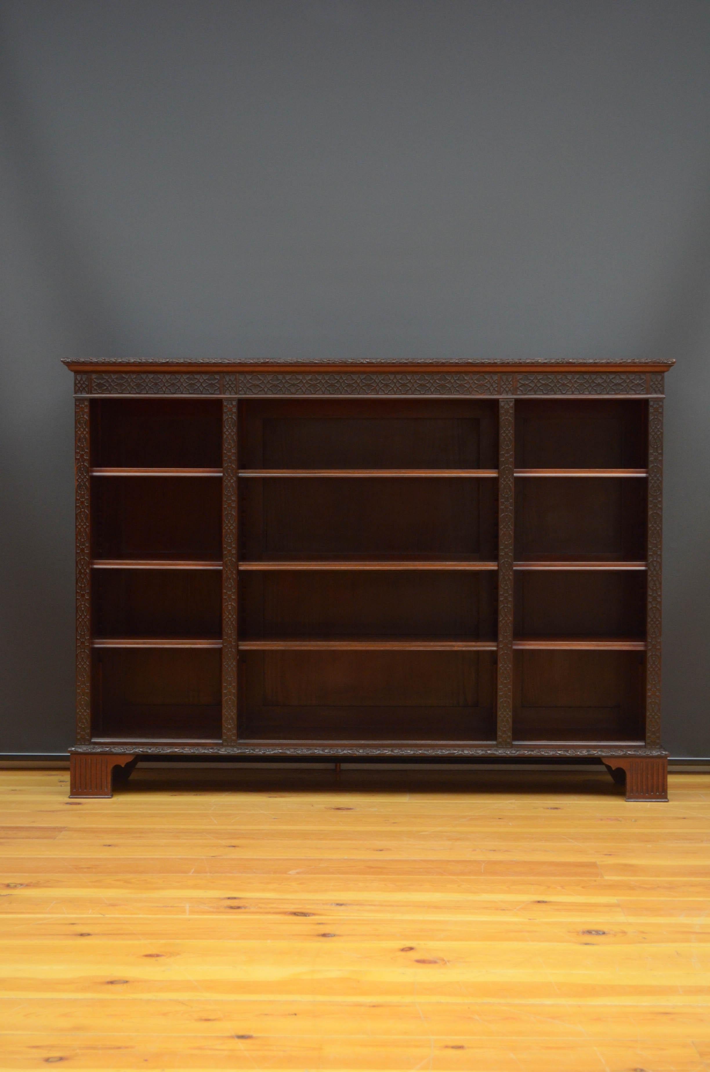 Sn5147, a quality Chippendale Revival open bookcase in mahogany, having oversailing top above finely carved moulding and blind fretwork frieze and three open section, each with three height adjustable shelves, all flamed by fretwork pilasters,