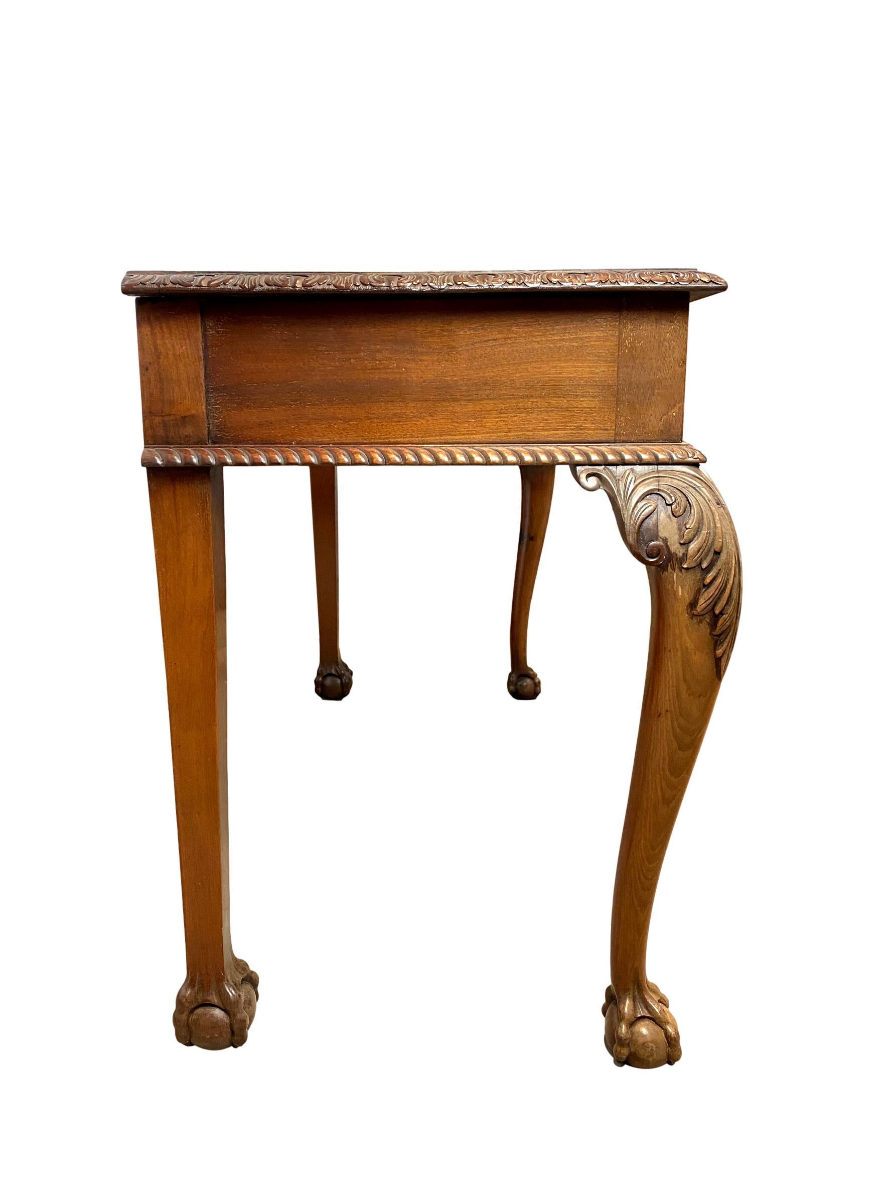 Chippendale Revival mahogany three-drawer console table, English, circa 1880, of bowed-front form, the top with stylized carved edging, above three drawers, with gadrooned edging below, on ball and claw feet.