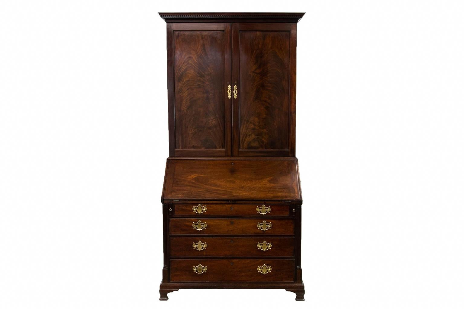 The top interior of this English Chippendale secretary has three adjustable shelves and five drawers. The interior has a center prospect door flanked by two secret pullouts with carved fluted pilasters. The cubbyhole friezes on either side are also