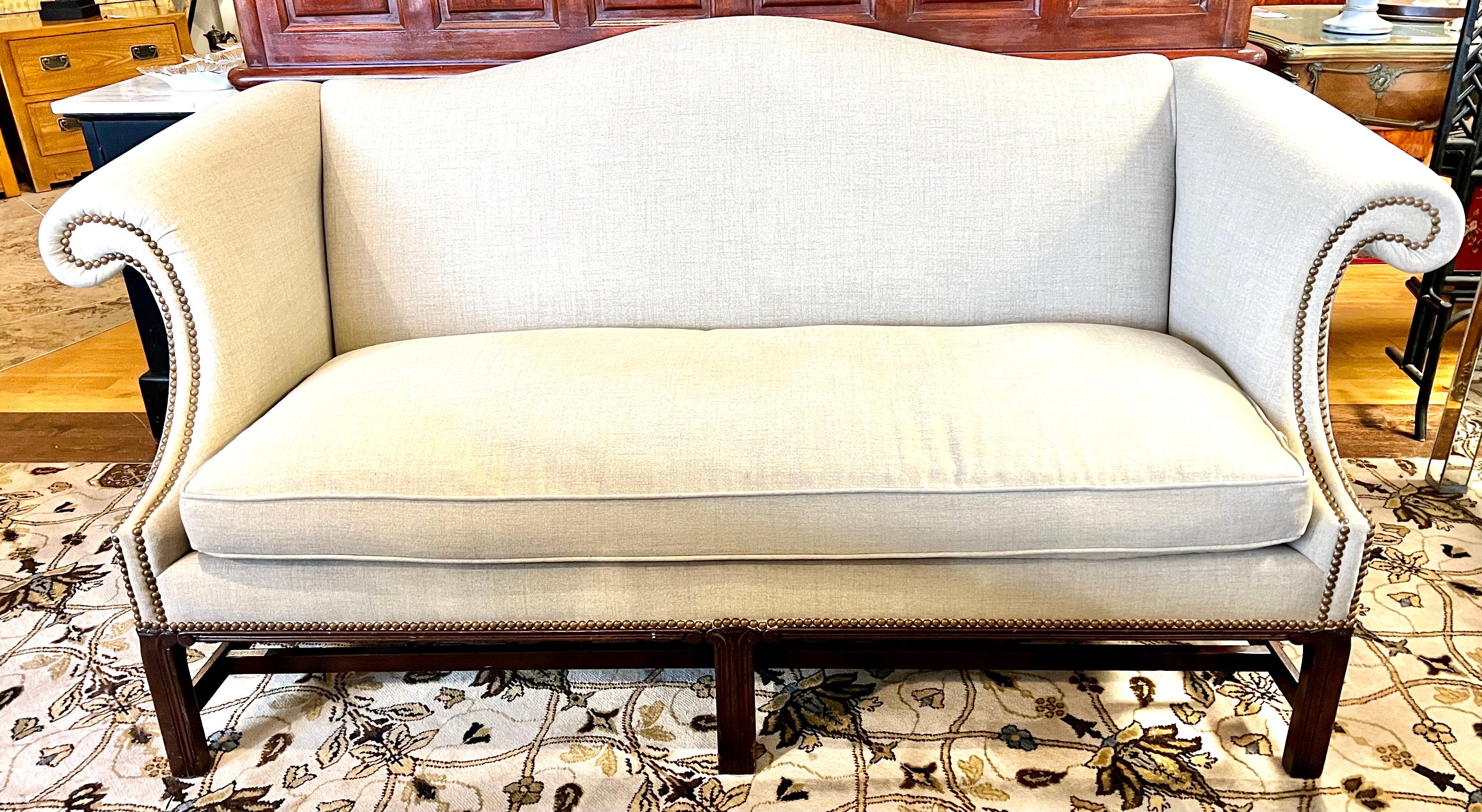 Elegant chippendale style camelback sofa with carved legs and stretcher. Has been recently upholstered in Crypton performance stain resistant fabric and finished with brass nailhead trim all around.