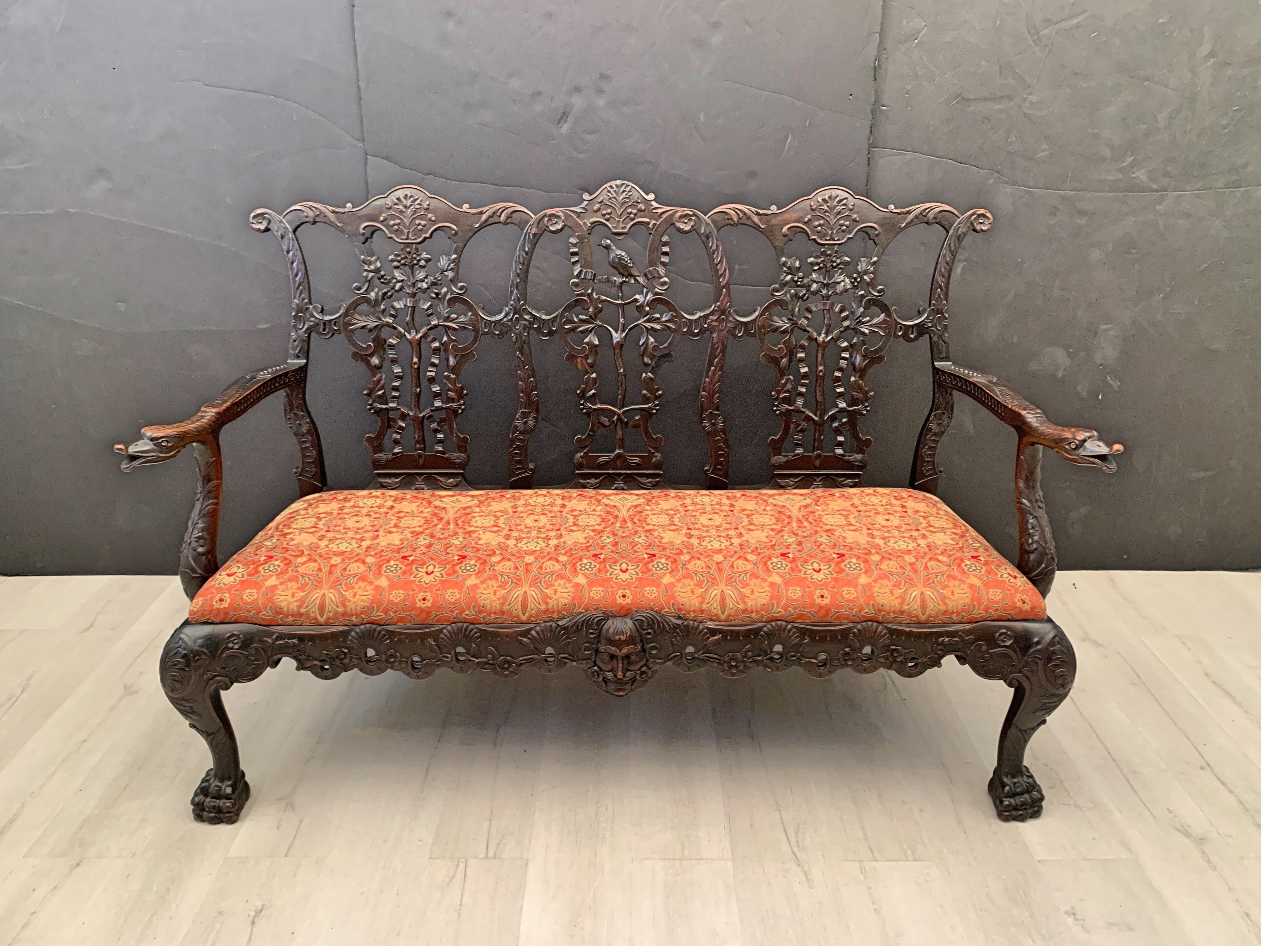 A carved mahogany Georgian Chippendale style triple back settee with ribbon back design, based on a design by Thomas Chippendale, late 19th century, England. 

The triple back settee finely and elaborately carved from a dark and lustrous mahogany,