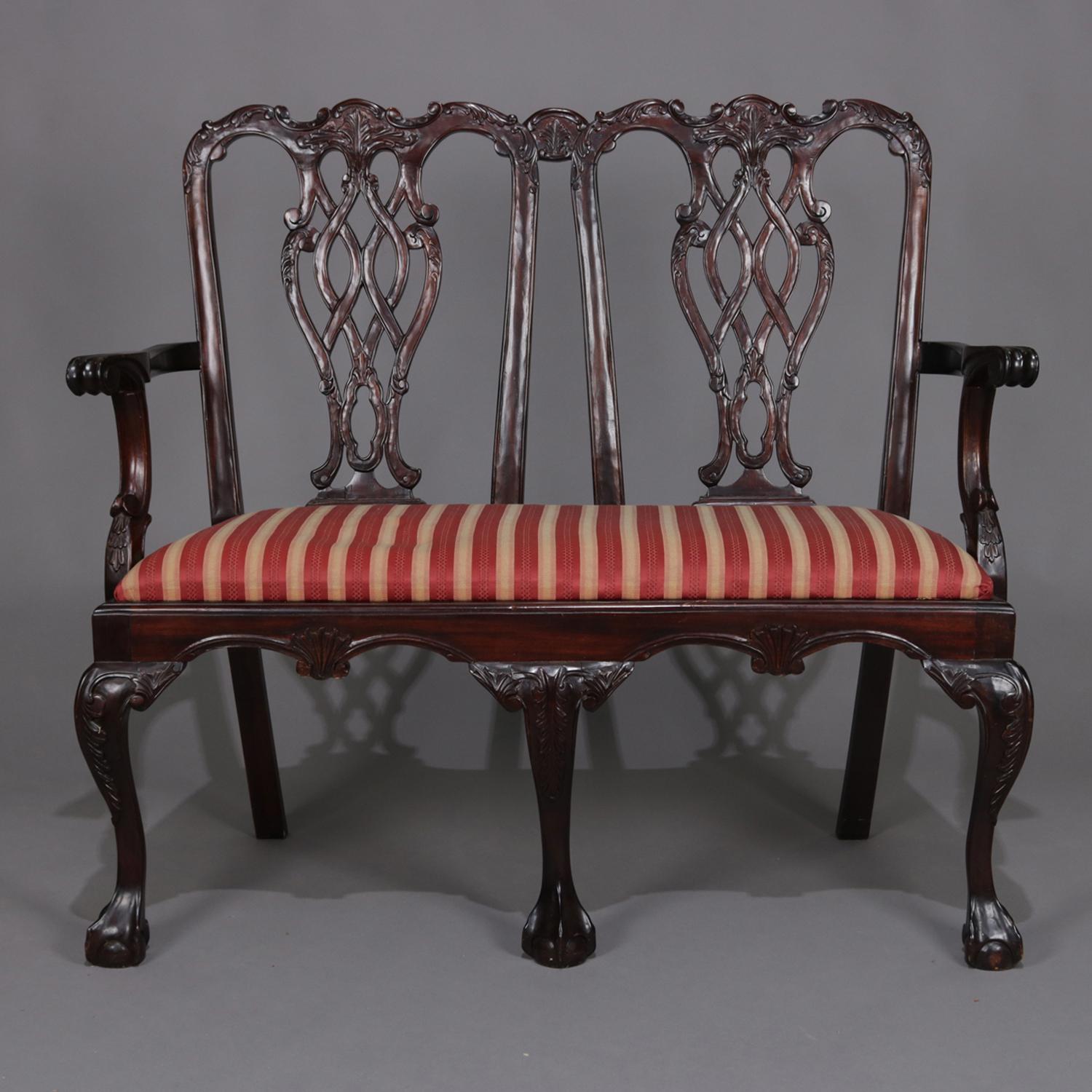 Chippendale style double chair settee features carved mahogany frame with ribbon back, scrolled arms, seated on claw and ball feet and with upholstered seat, 20th century

***DELIVERY NOTICE – Due to COVID-19 we are employing NO-CONTACT PRACTICES in