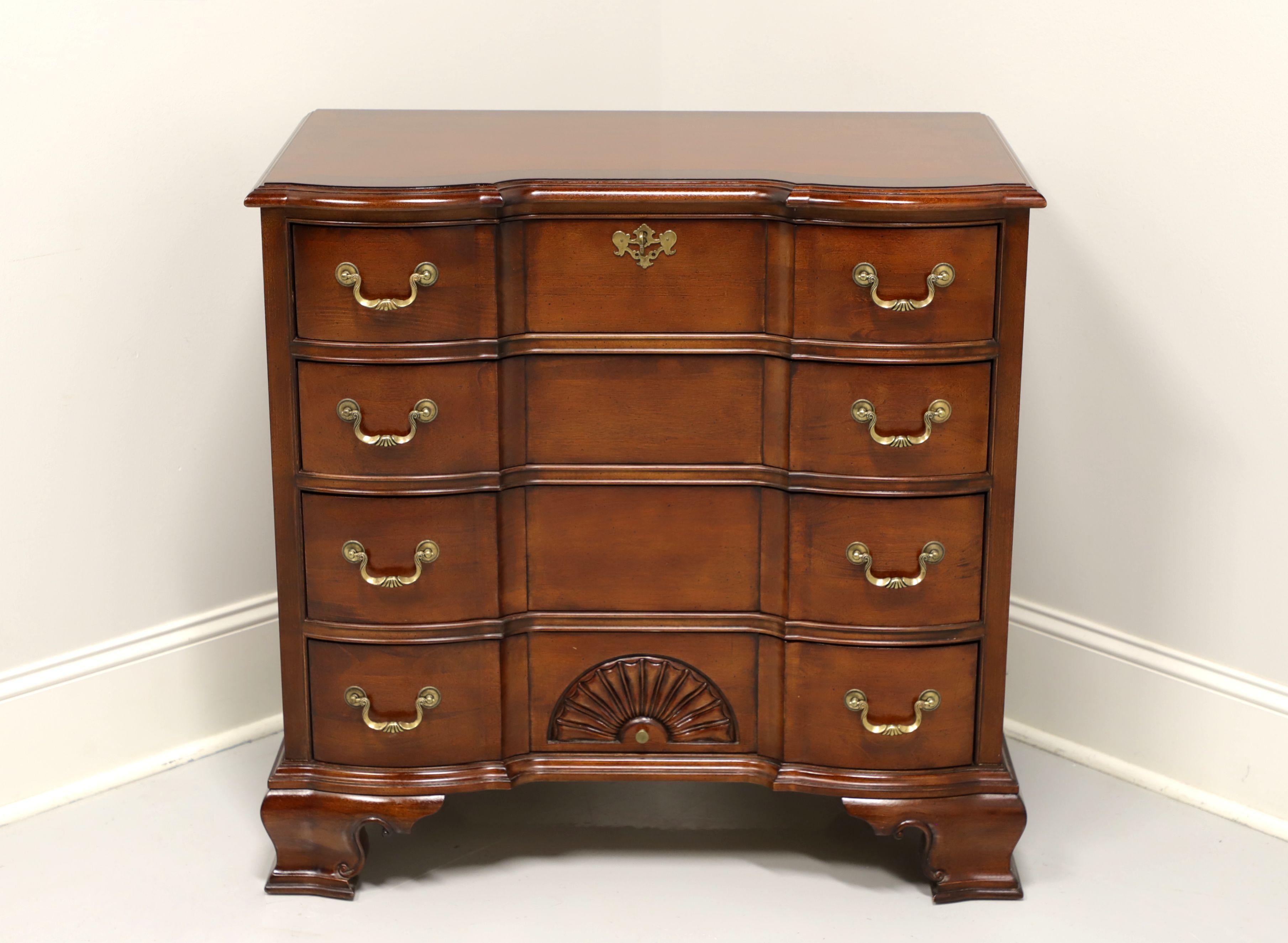 A Chippendale style block front bedside chest, unbranded. Cherry with brass hardware, open fan carving and ogee bracket feet. Features four drawers of dovetail construction, top drawer being lockable. Includes one key. Made in Asia, in the early
